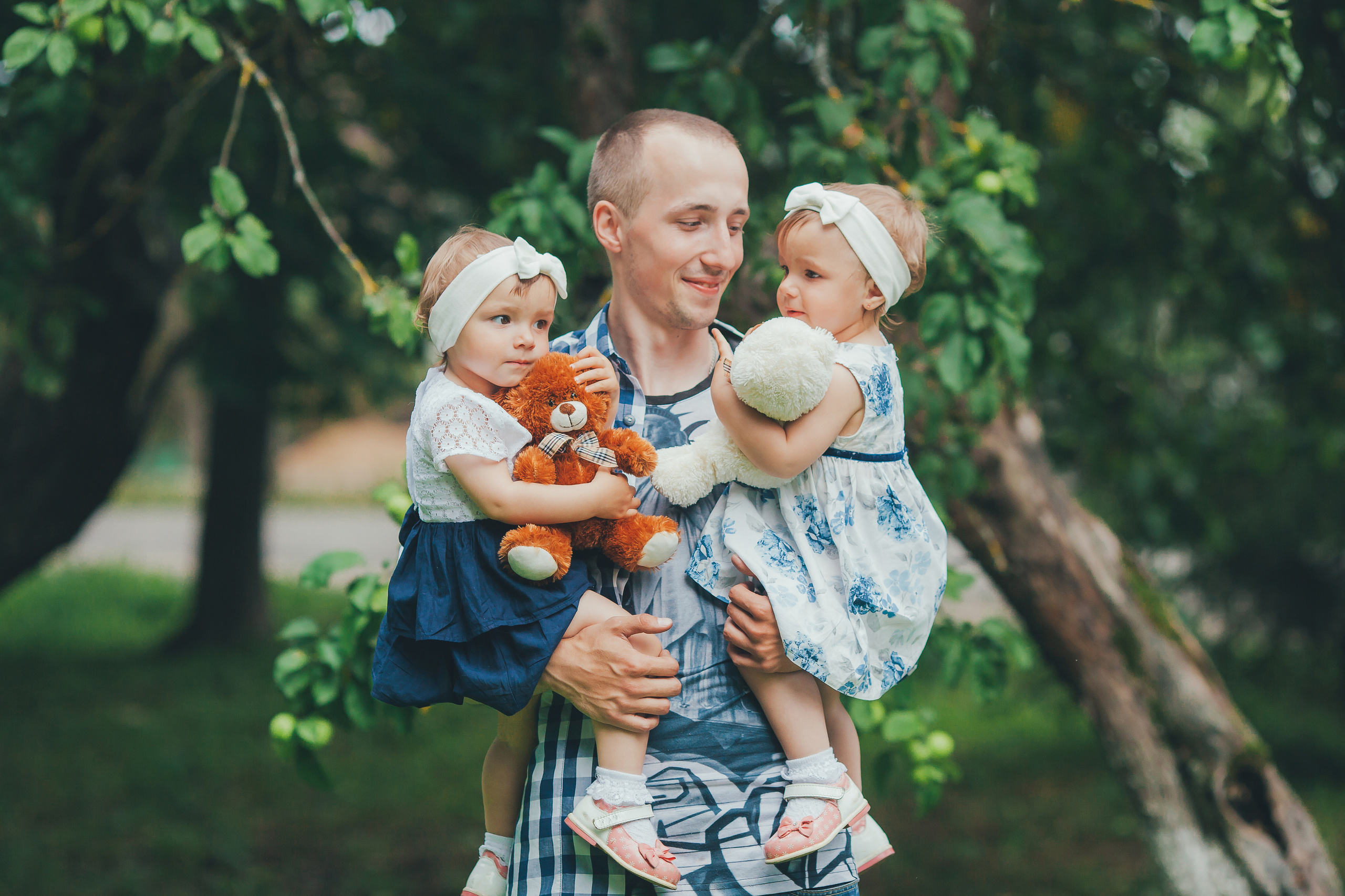 Счастливый отец с двумя малышками в яблоневом саду Смоленска