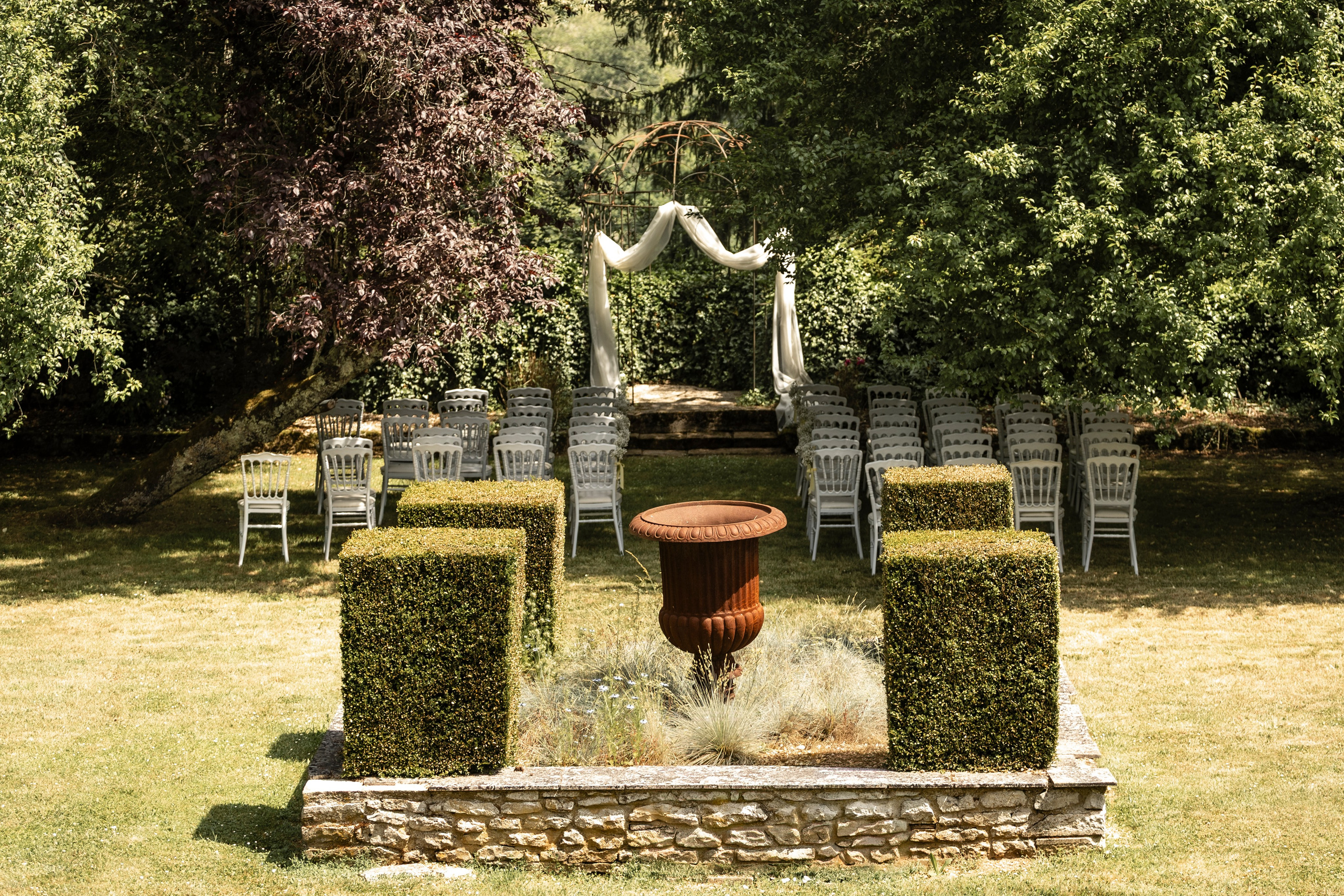Clipped hedges and a stone urn in the château garden before the ceremony
