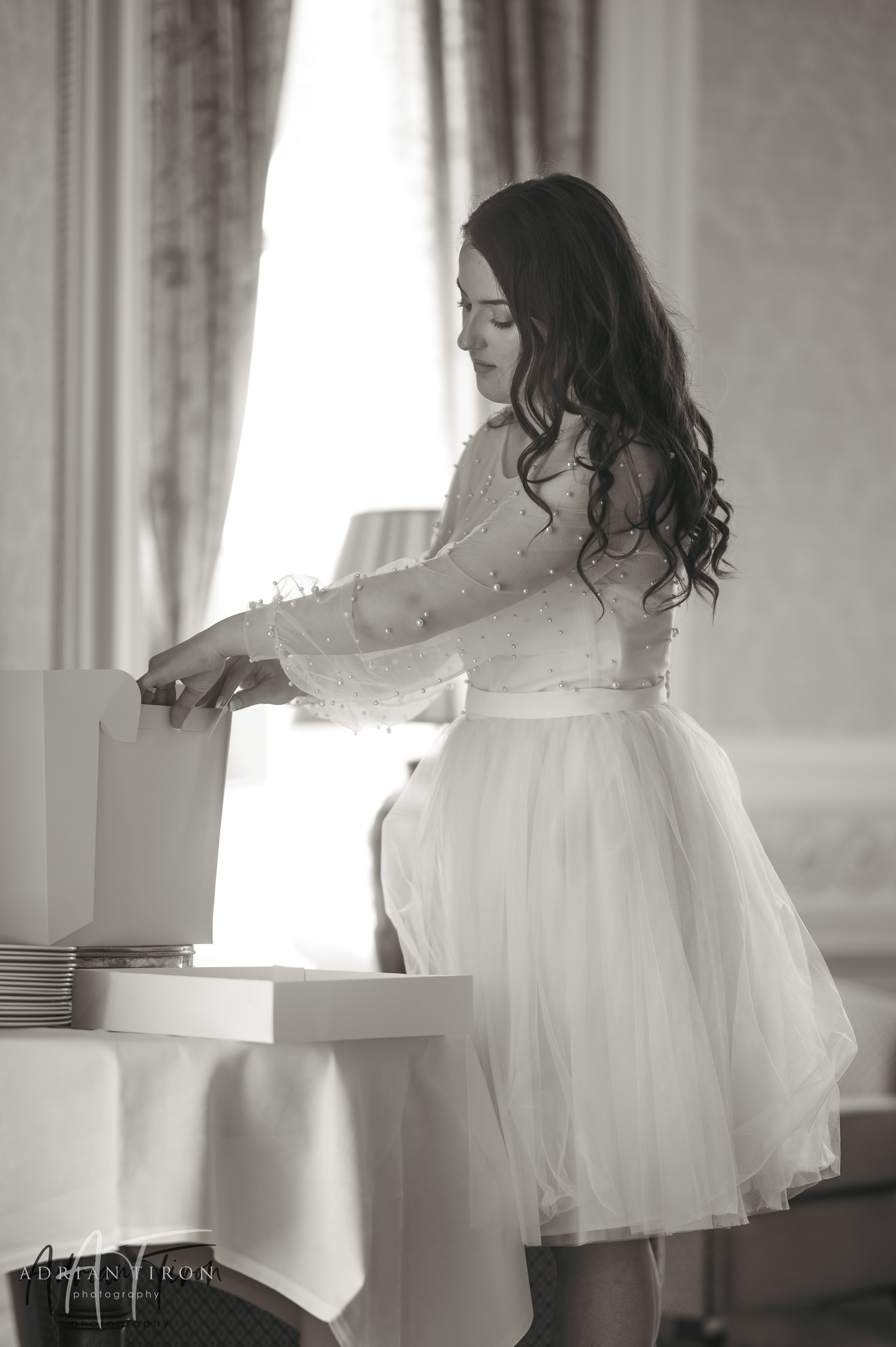 Bride arranging items by a sunlit window at Luton Hoo