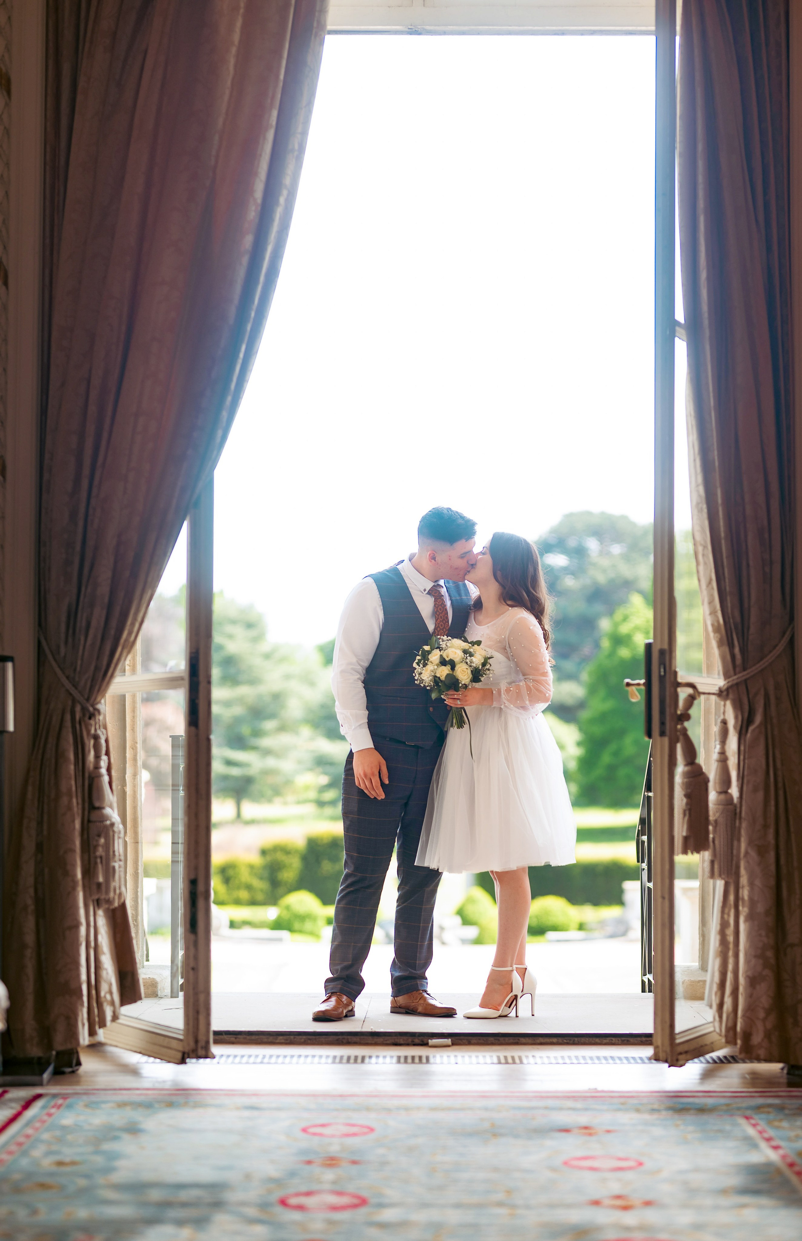 Bride and groom sharing a kiss in a garden doorway at Luton Hoo