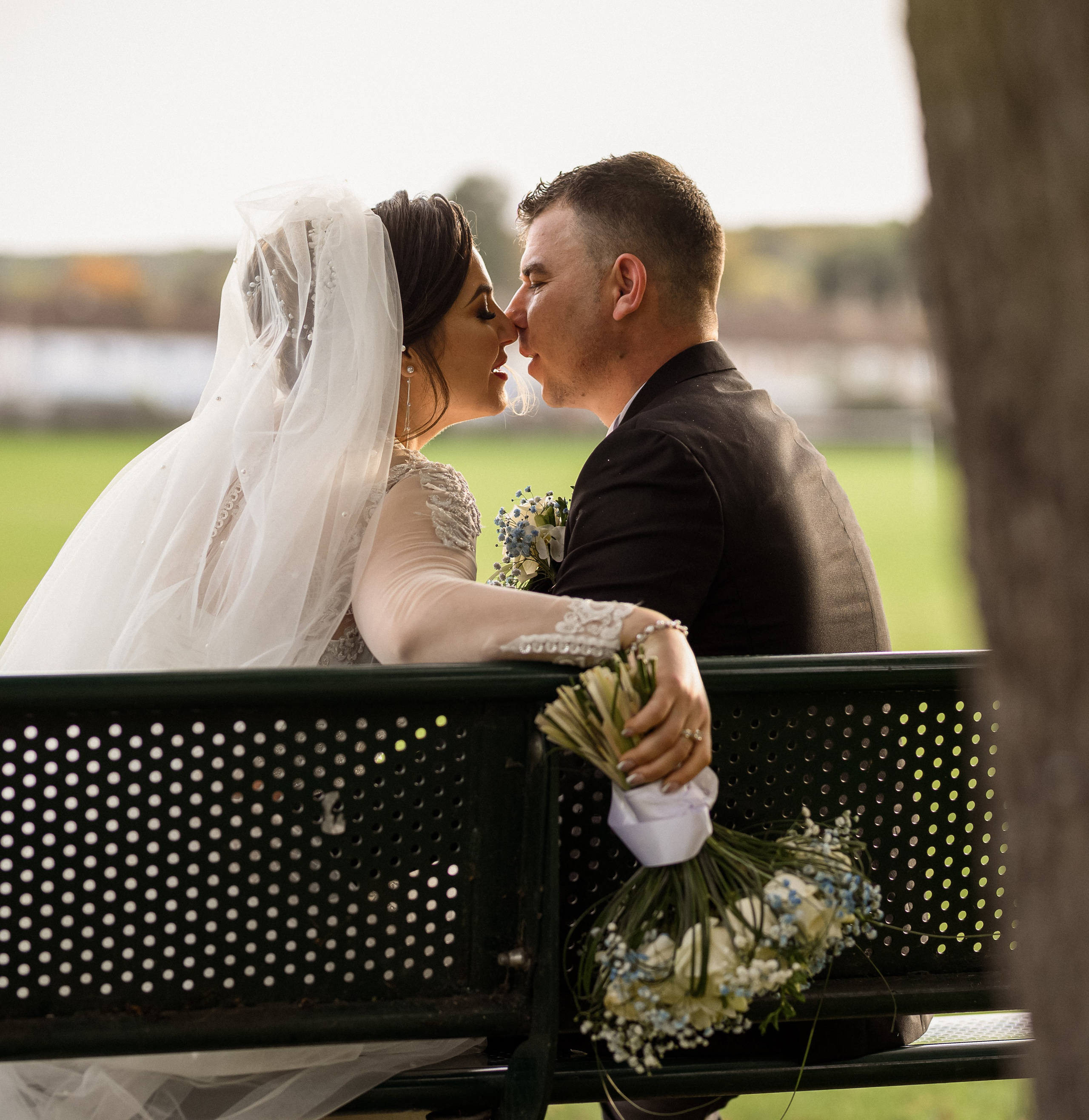 Bride and groom sharing a close moment on a park bench after the ceremony