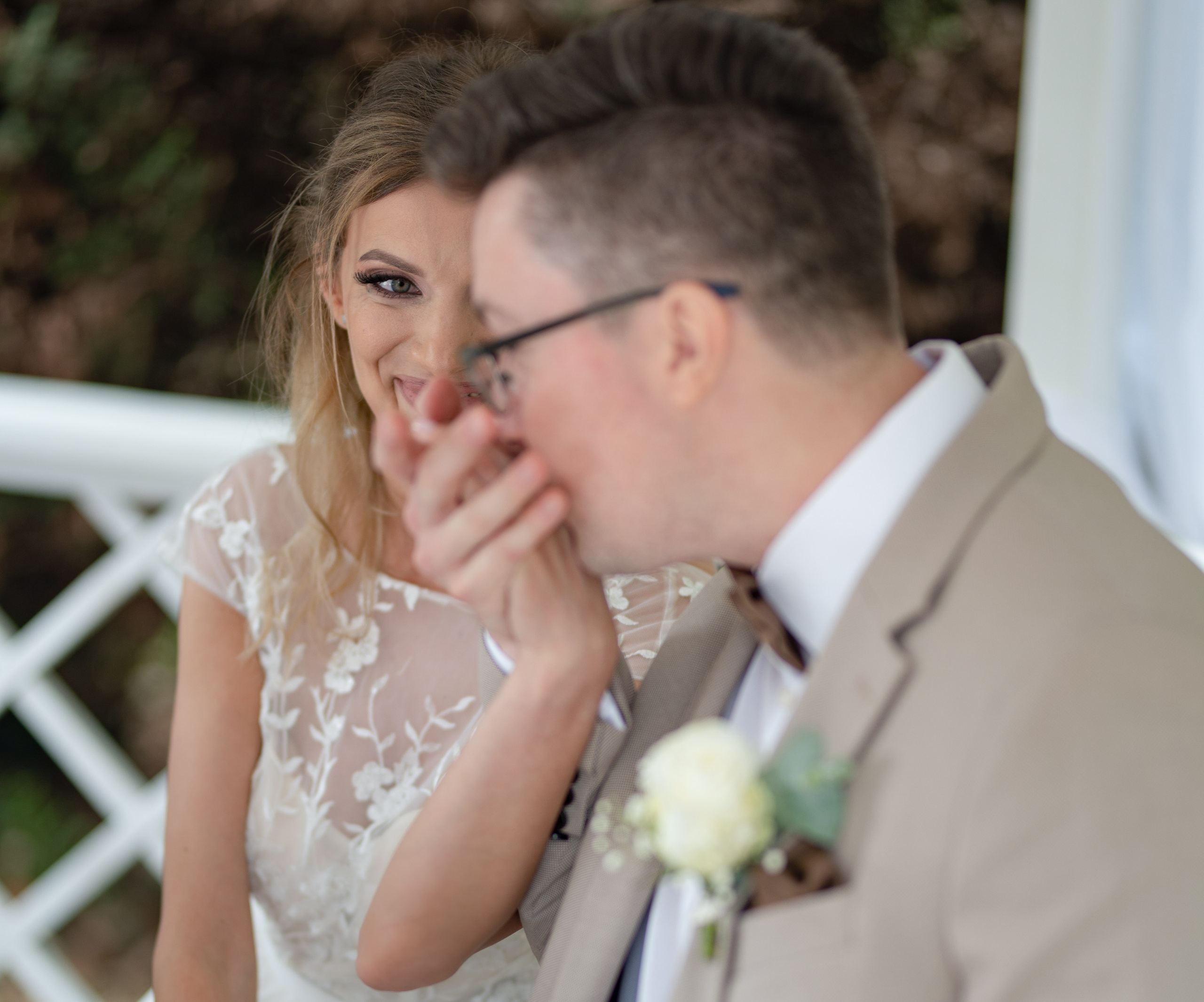 Bride laughing as the groom whispers to her during the ceremony, close-up