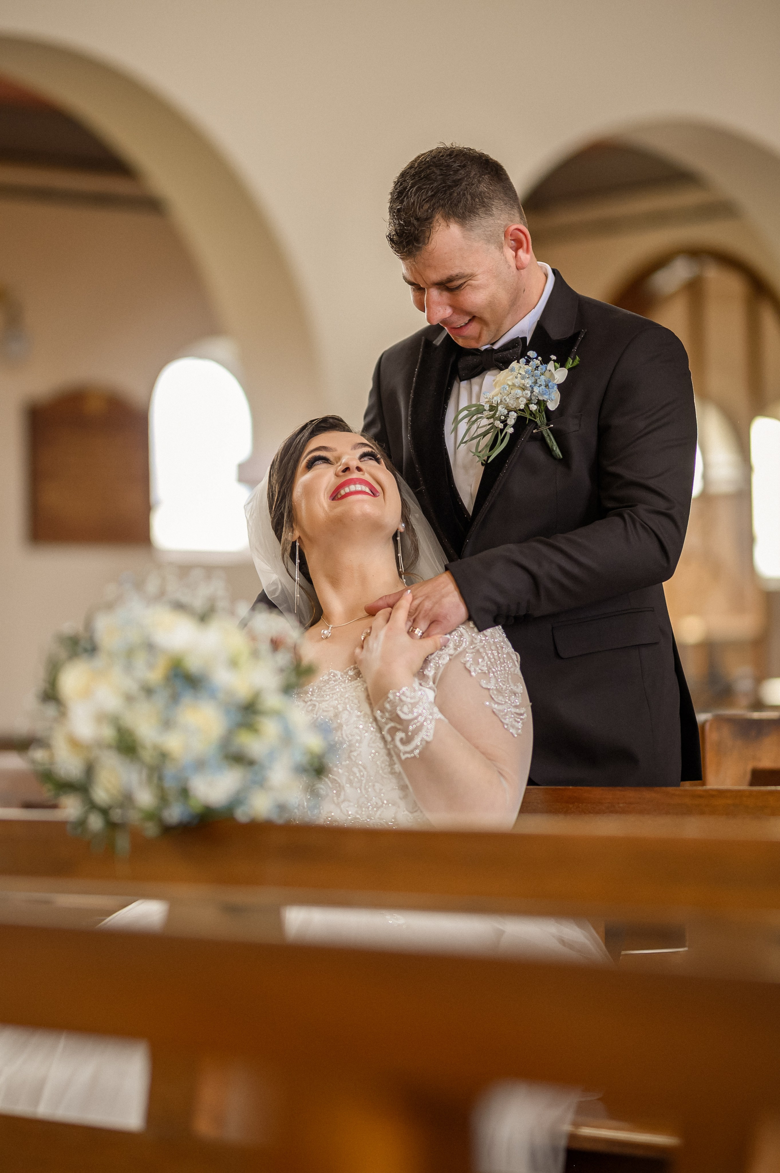 Groom sharing a laugh with his best man in a church pew before the ceremony