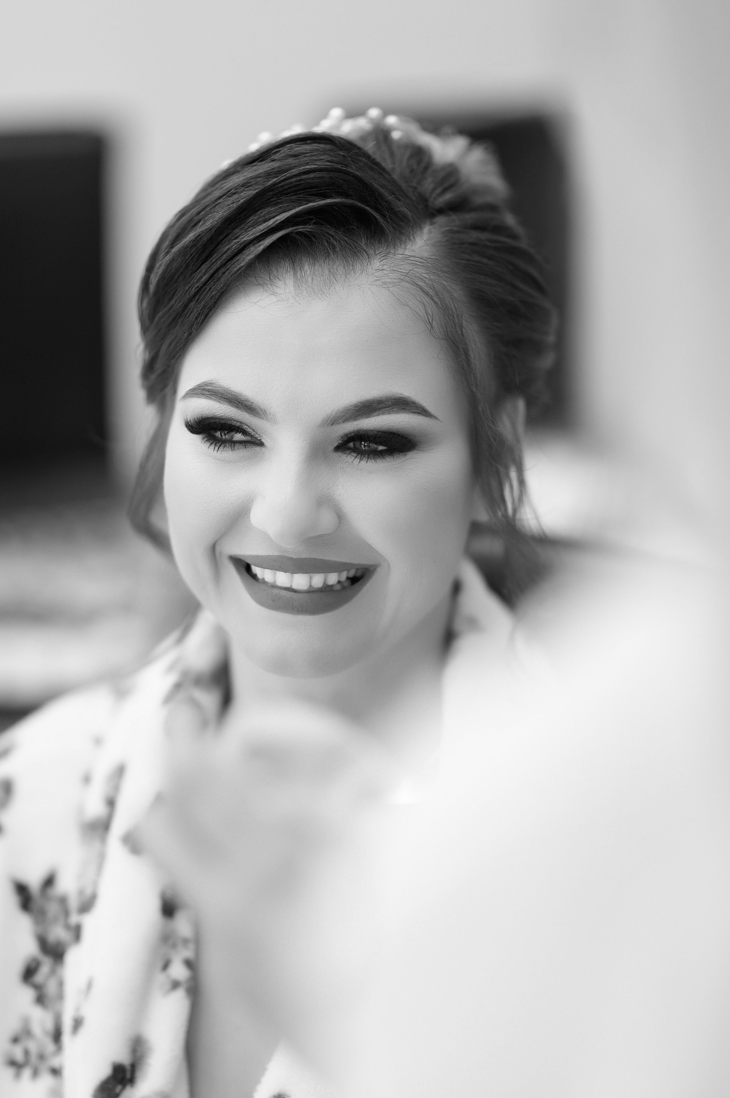 Close-up portrait of the smiling bride with soft flowers blurred in the foreground