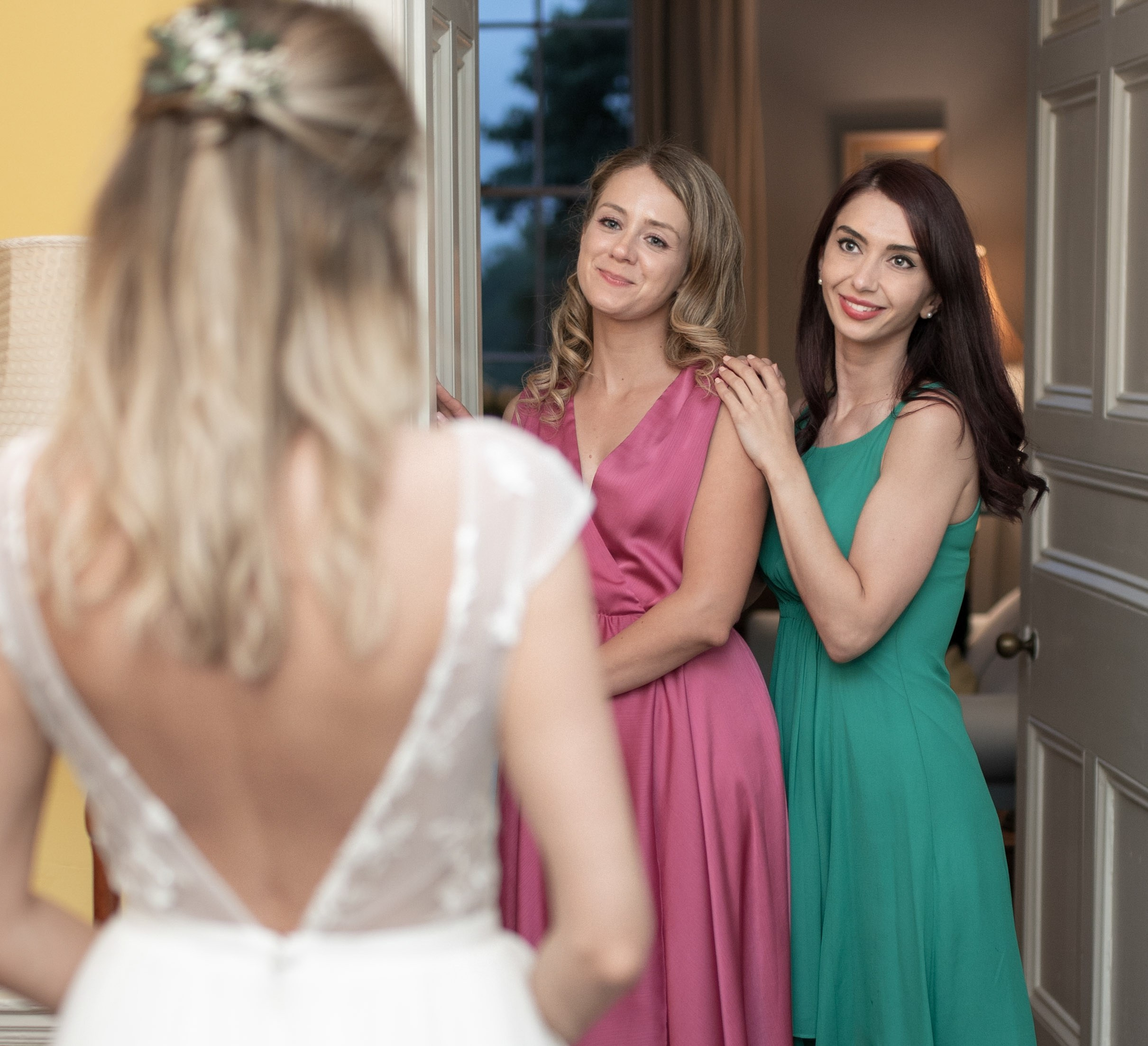 Bridesmaids in pink and green smiling at the bride, close-up