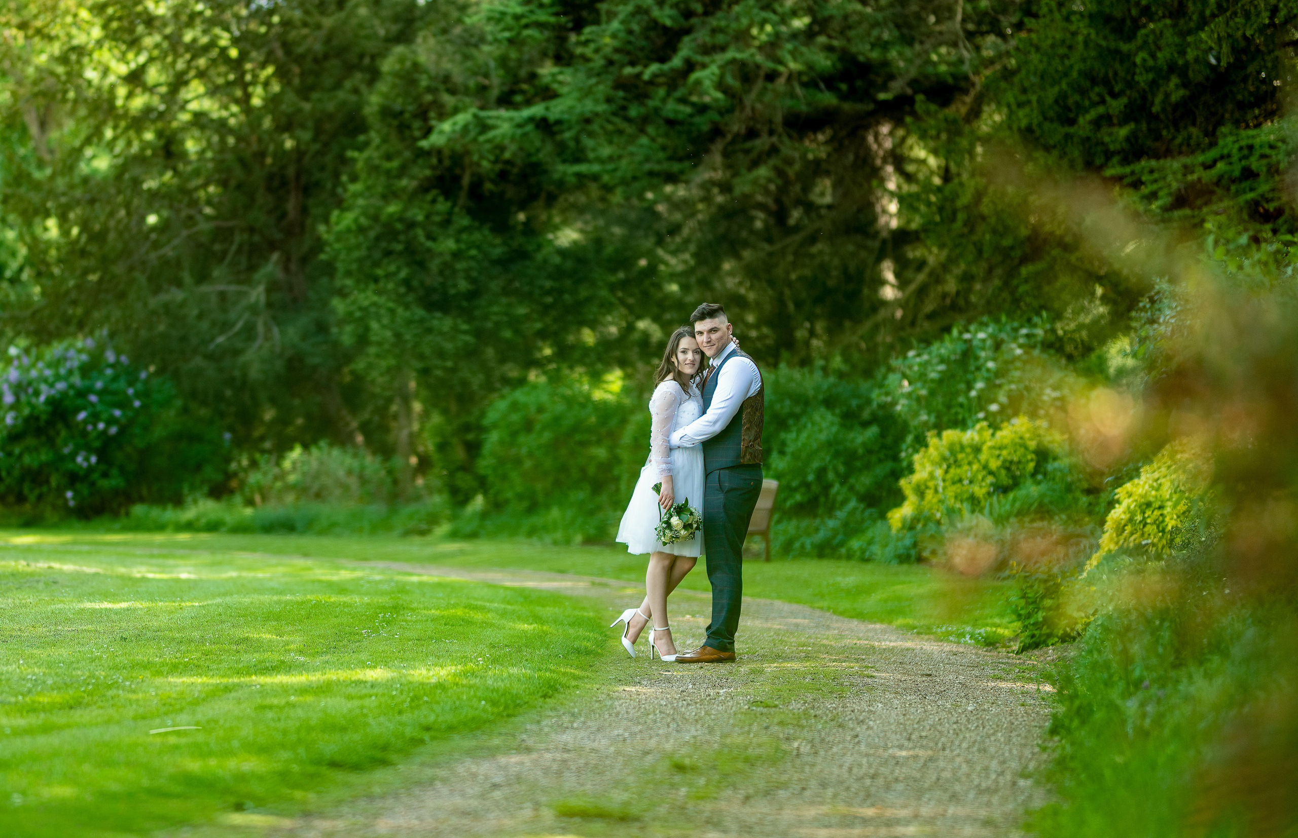 Bride and groom walking arm in arm along a tree-lined path in the grounds of Luton Hoo, Bedfordshire