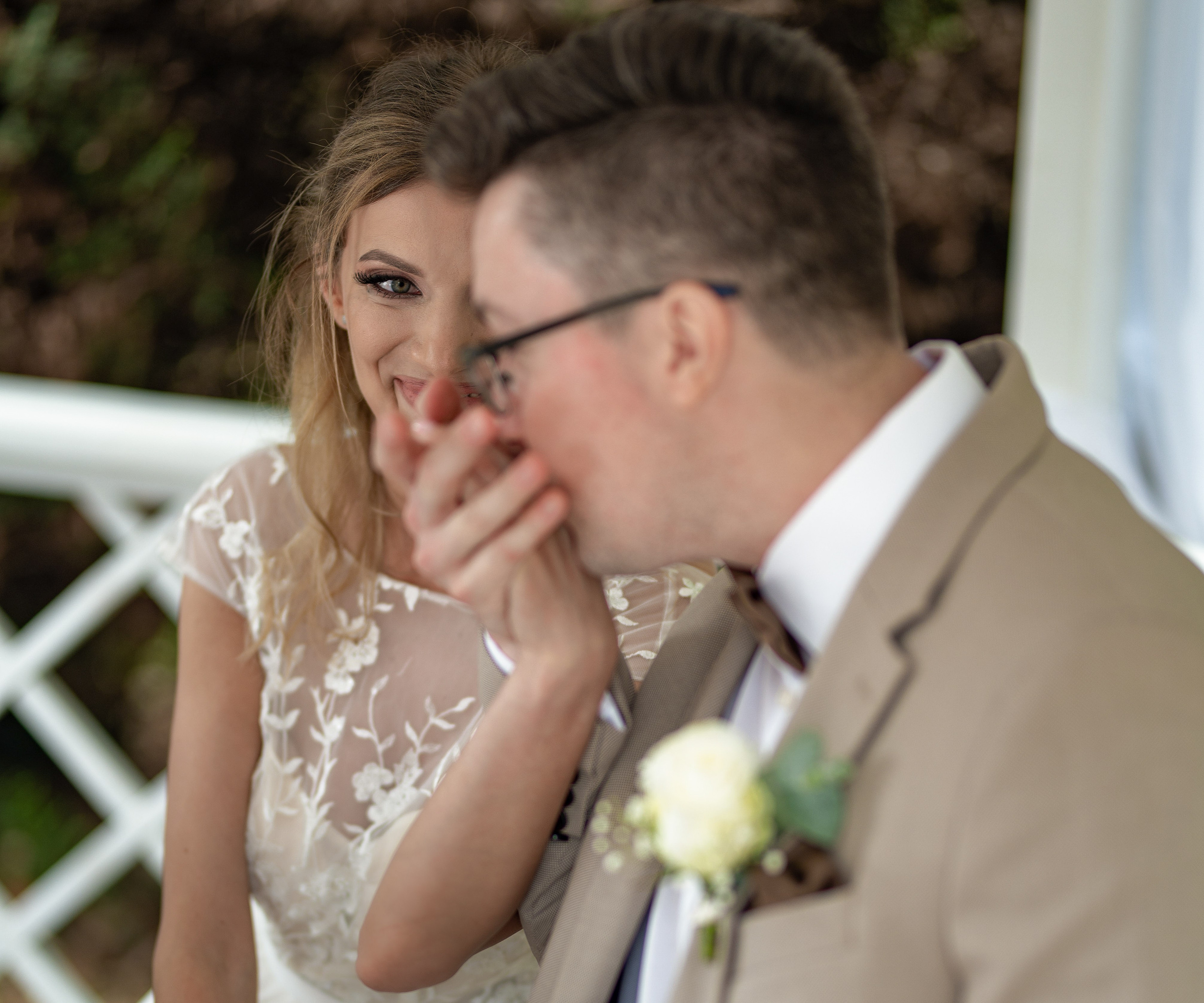 Bride laughing as the groom whispers to her under the gazebo, playful close-up