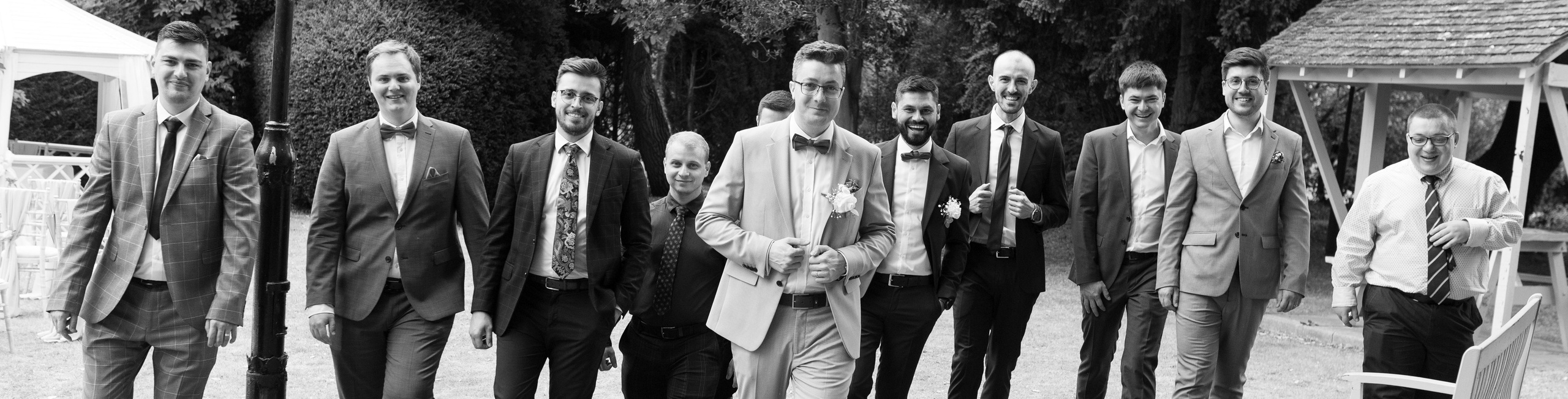 Groom walking with his groomsmen across the lawn at Charlecote Pheasant Hotel (black and white)