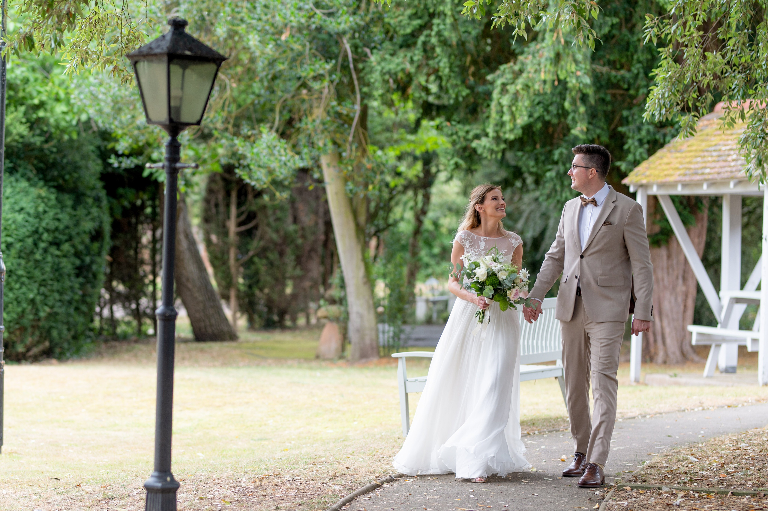 Bride and groom walking hand in hand through the grounds, laughing together