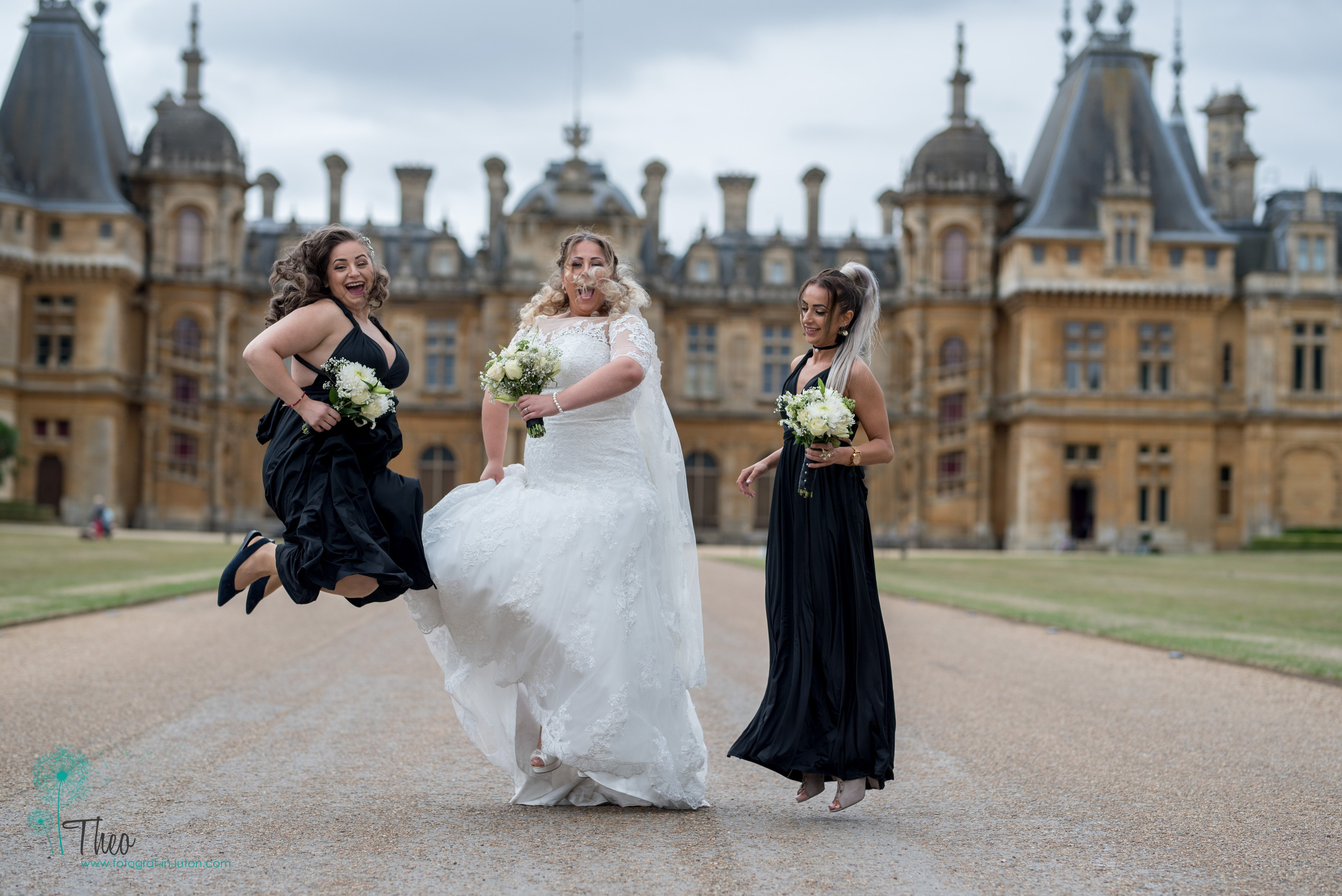 Bride Andrada and her bridesmaids in black gowns leap for joy on the driveway in front of Waddesdon Manor, Buckinghamshire