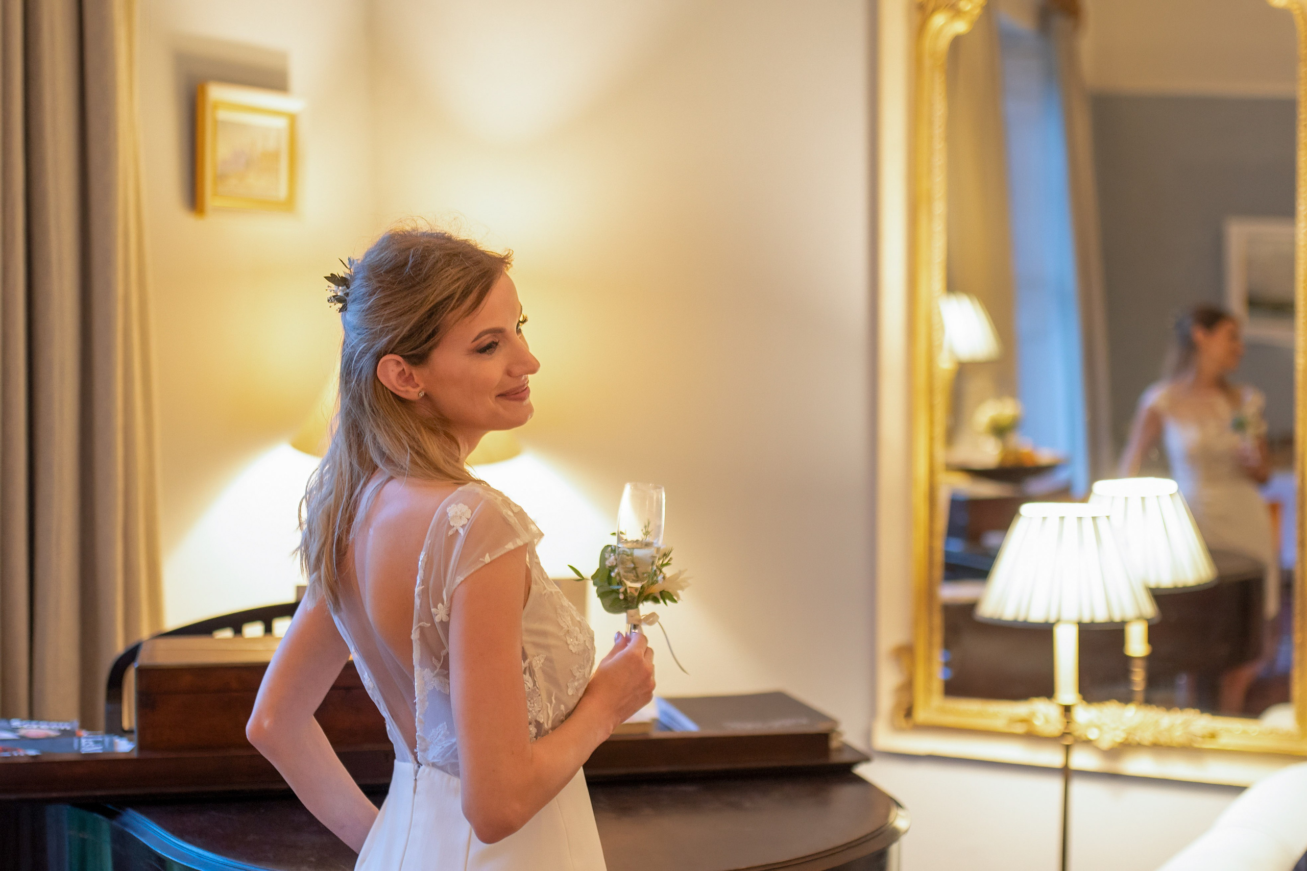 Bride smiling over her shoulder with a glass of champagne in the warm evening light