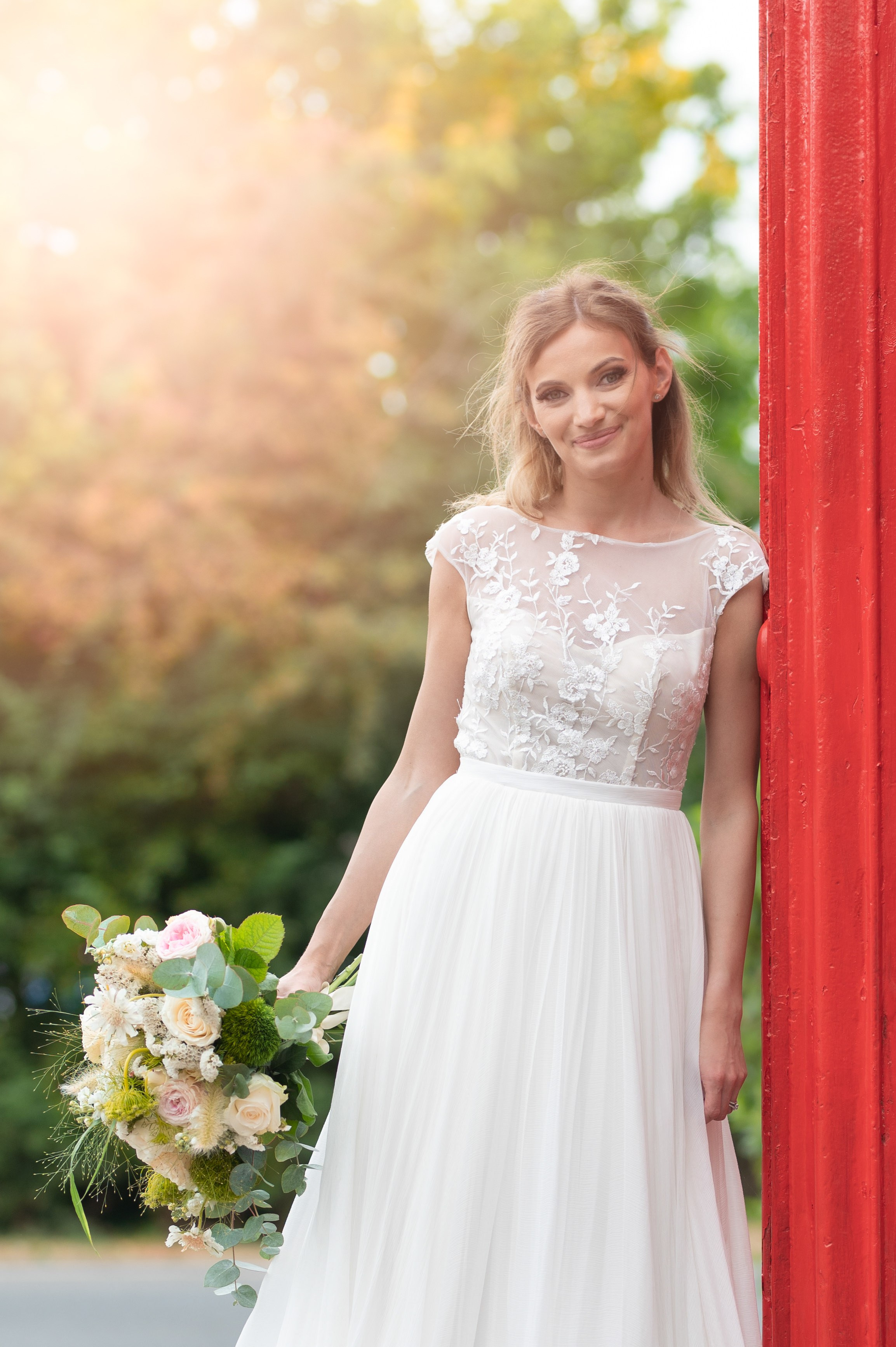 Close bridal portrait by the red phone box, warm golden-hour light