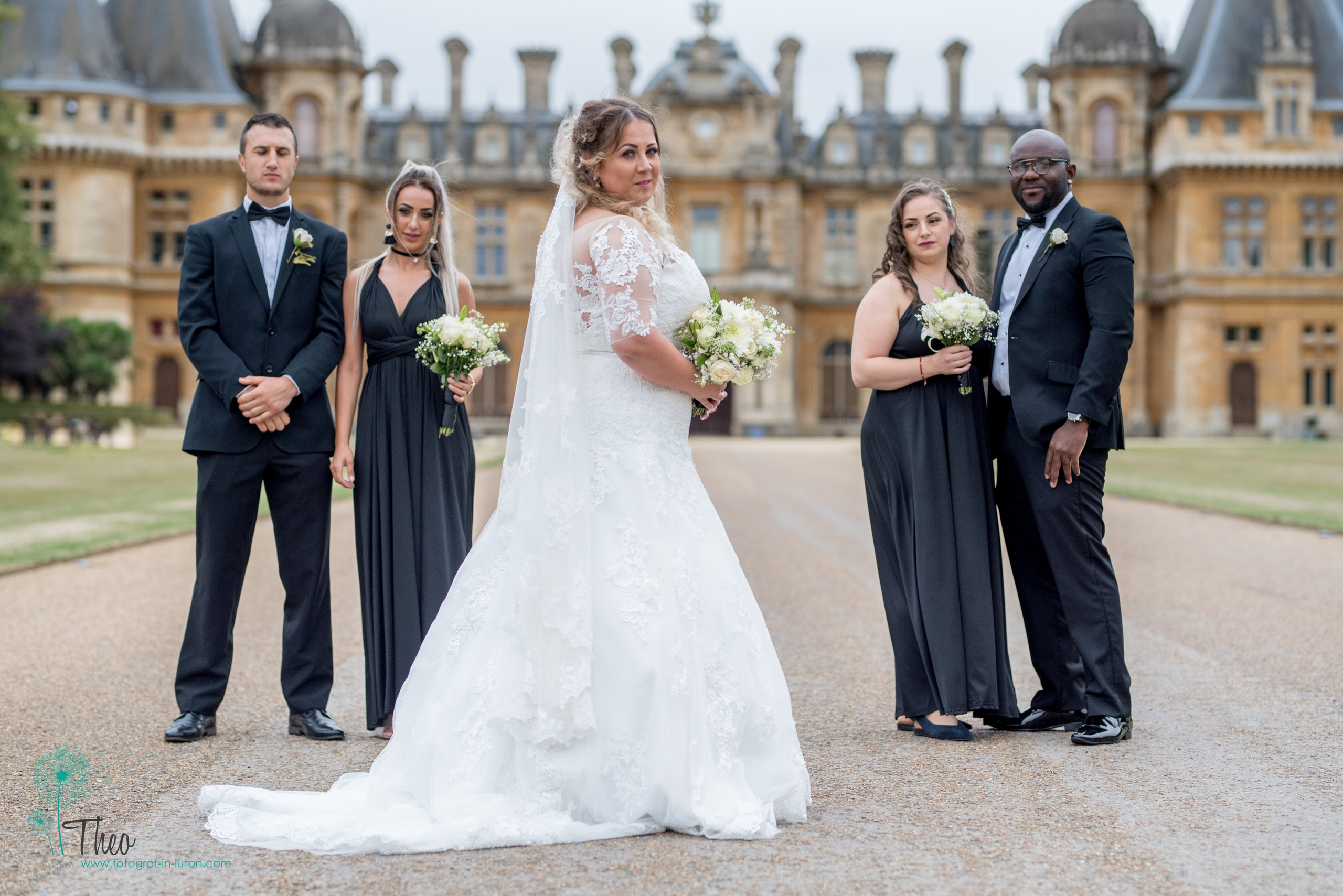 The bride and her wedding party pose together on the long drive in front of Waddesdon Manor's ornate facade