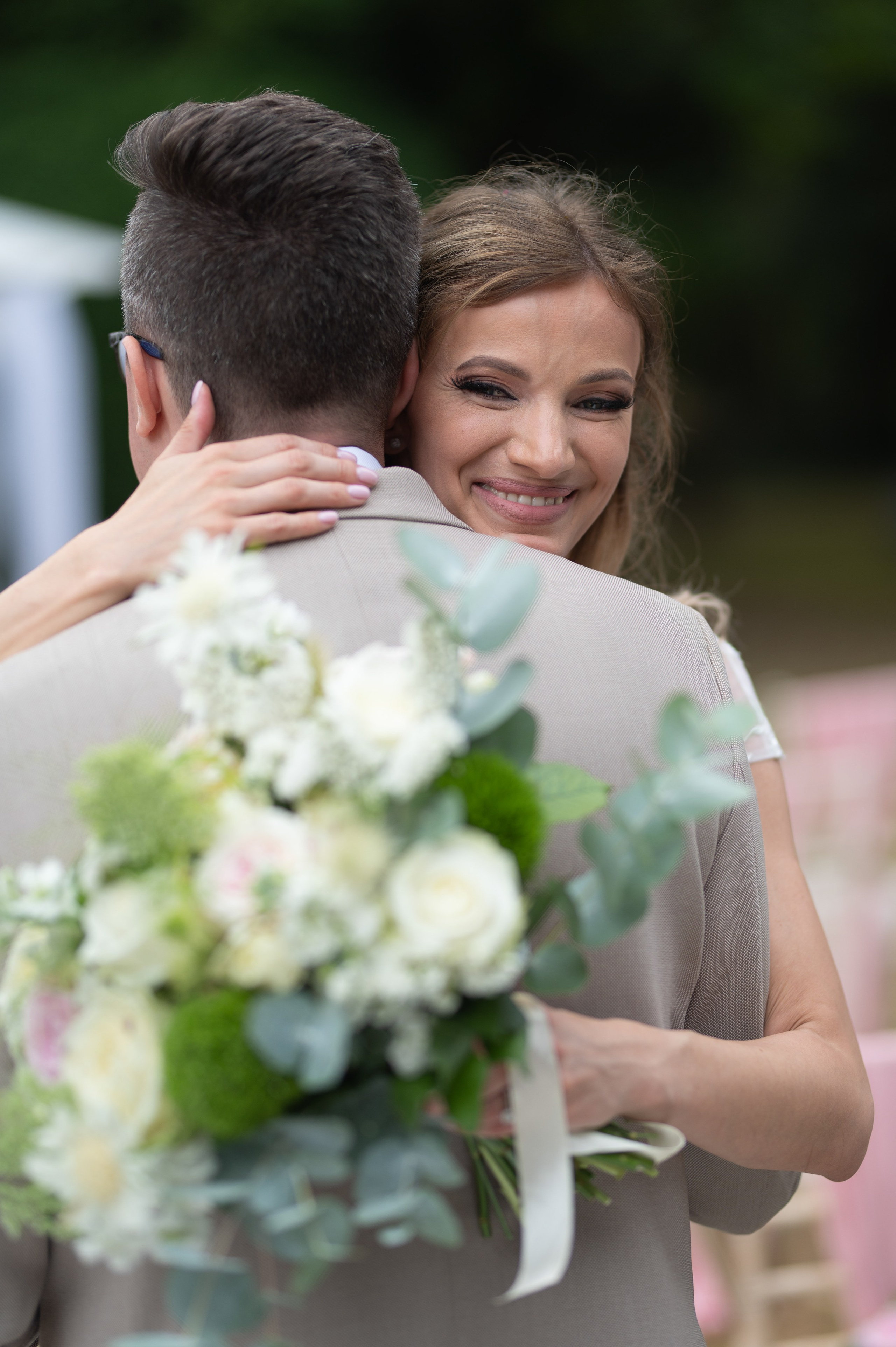 Bride and groom sharing an emotional hug, bride smiling with her arms around him
