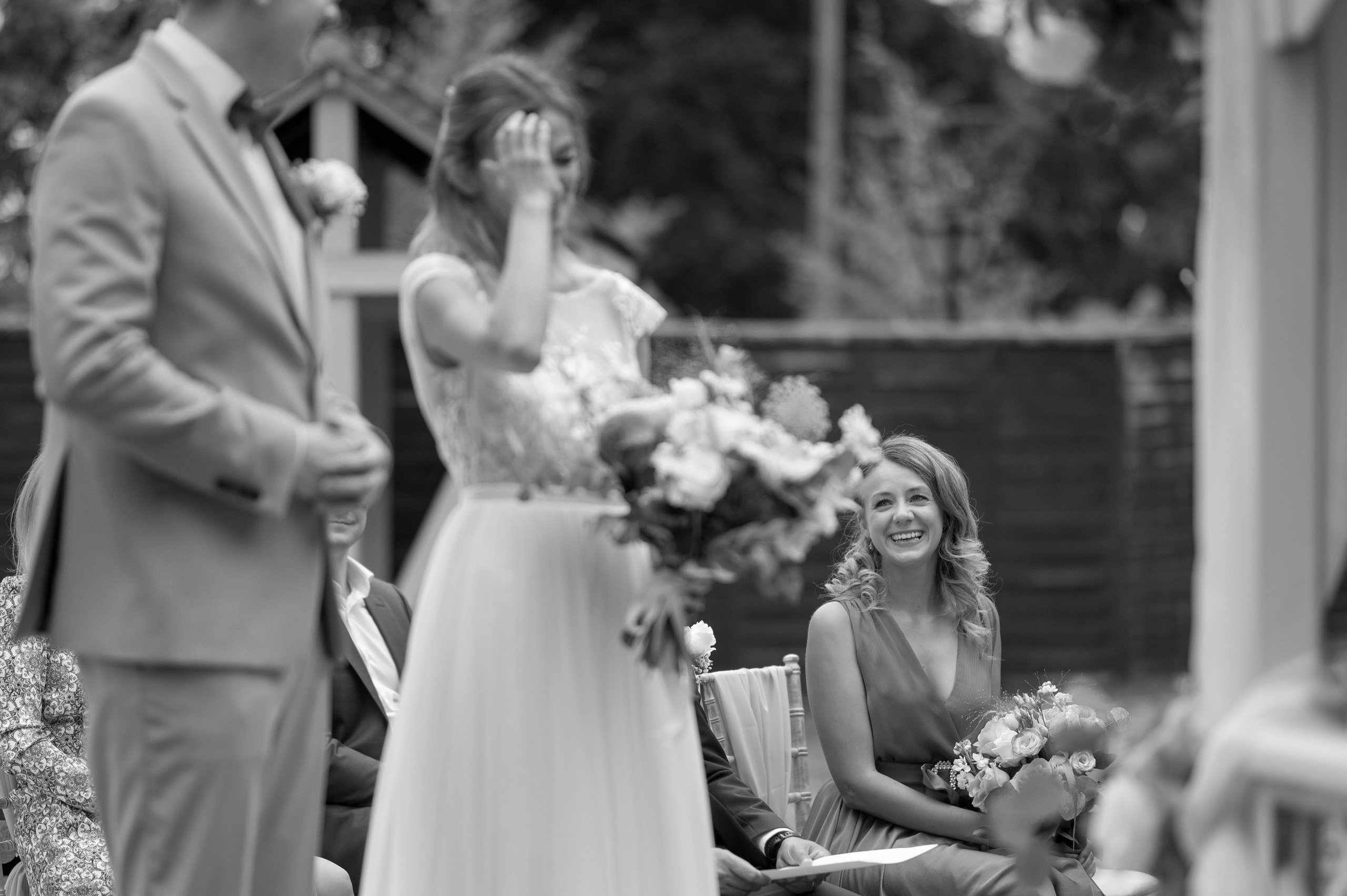 Emotional moment as the bride wipes away a happy tear during the ceremony vows (black and white)