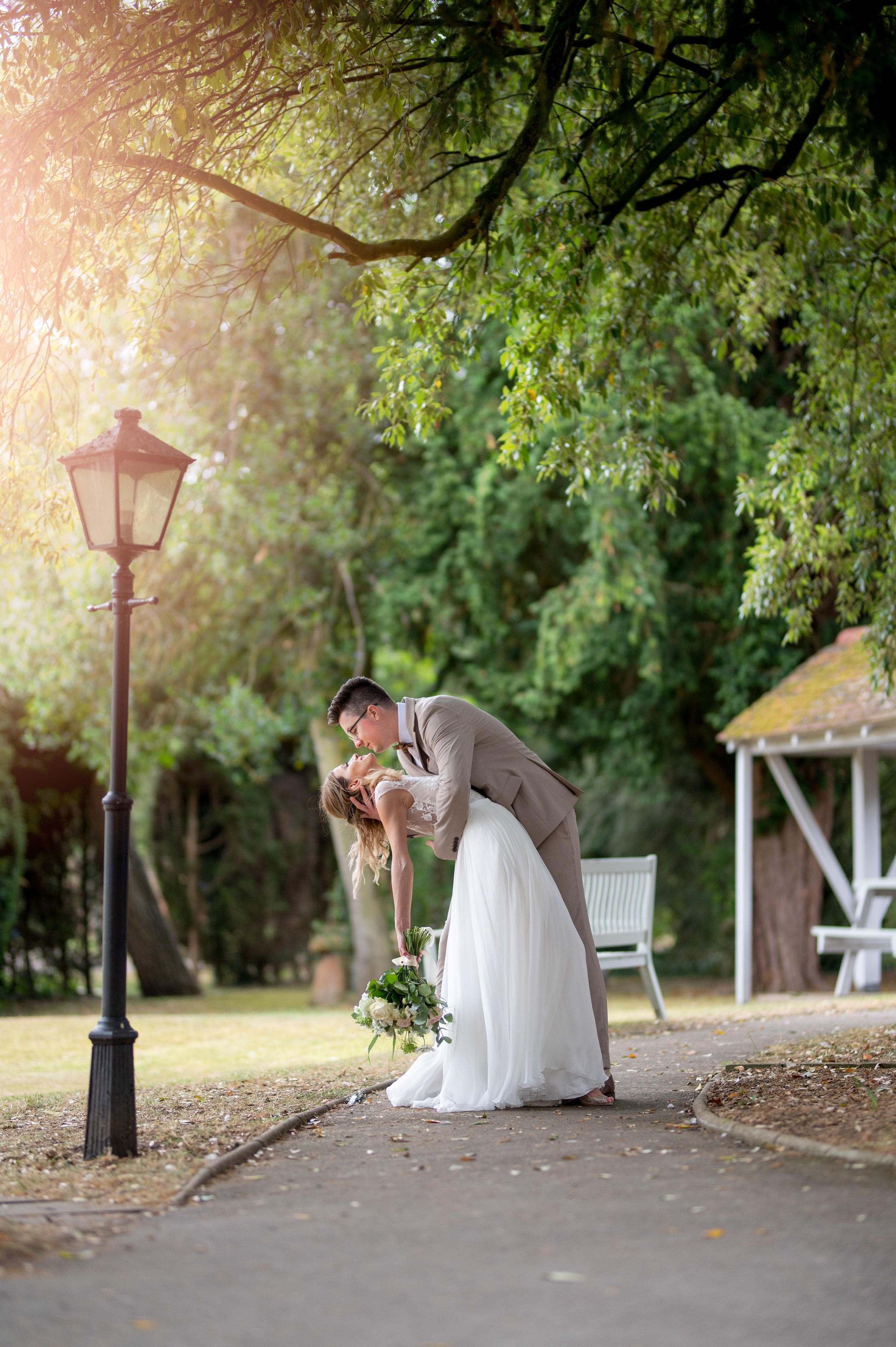 Golden-hour dip kiss between the newlyweds under the trees at Charlecote Pheasant Hotel