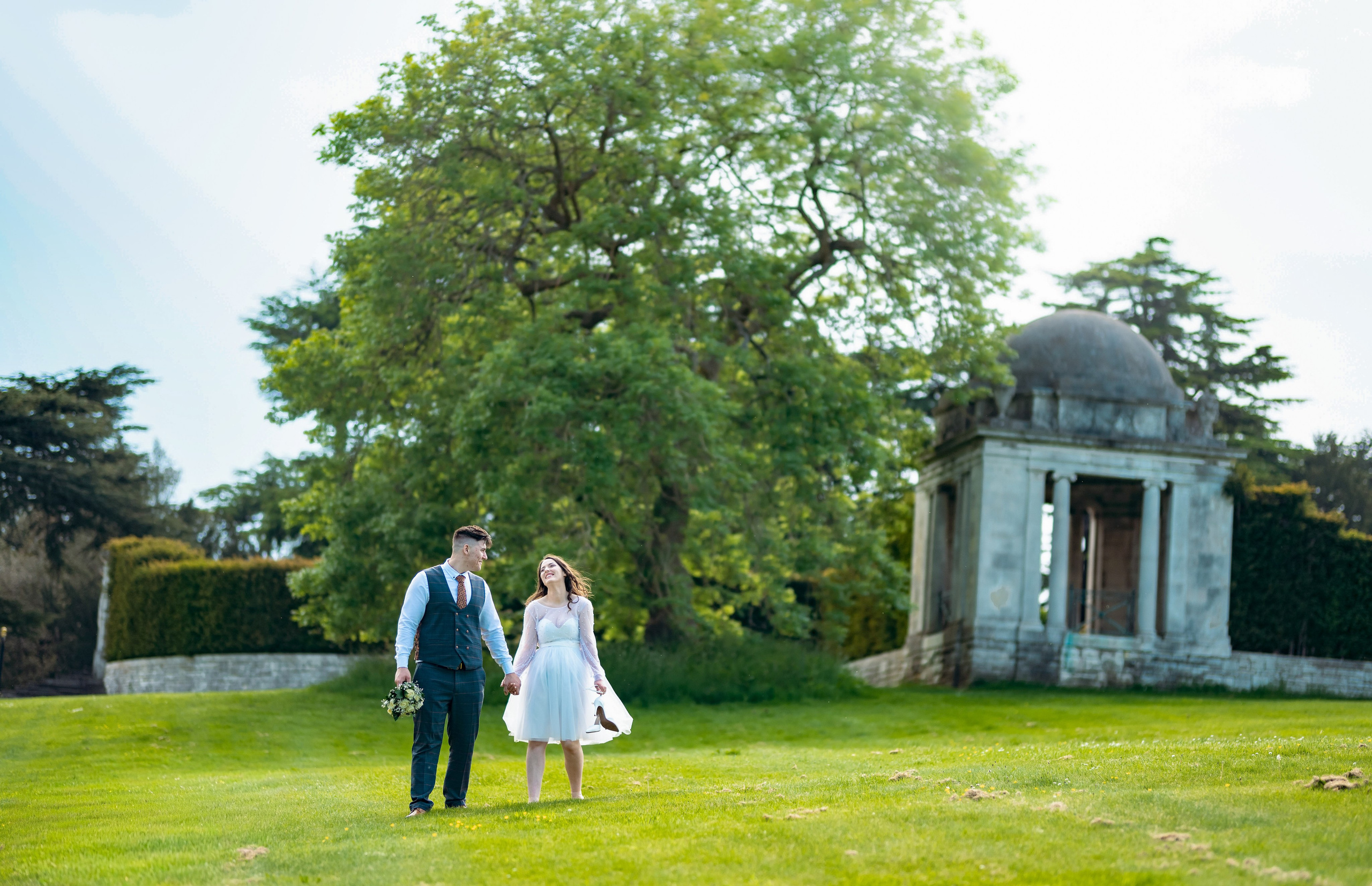 Bride and groom beneath a large tree on the grounds of Luton Hoo