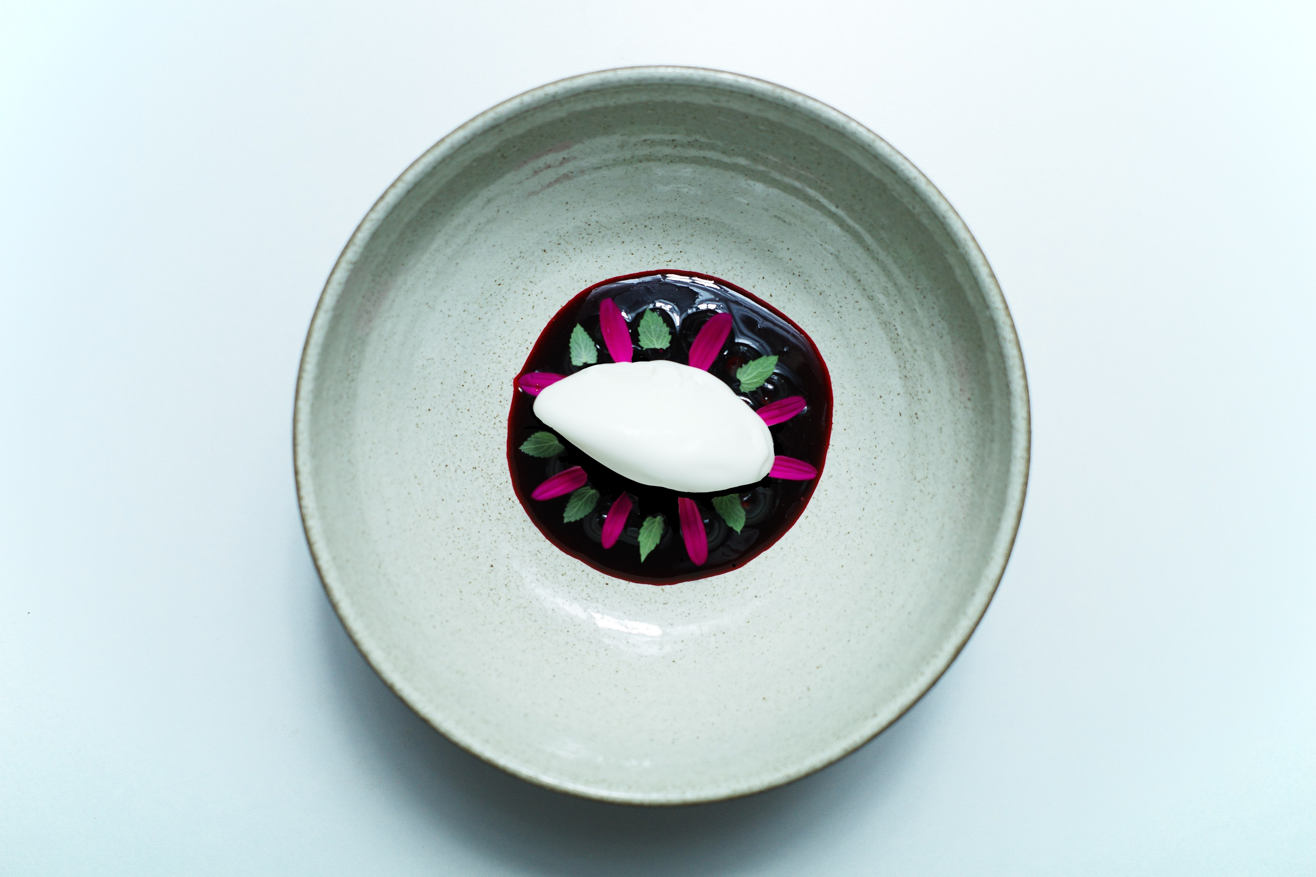 Silky cream with local juneberries , a quenelle of dairy ice cream, and a refined garnish of mint and edible flowers.