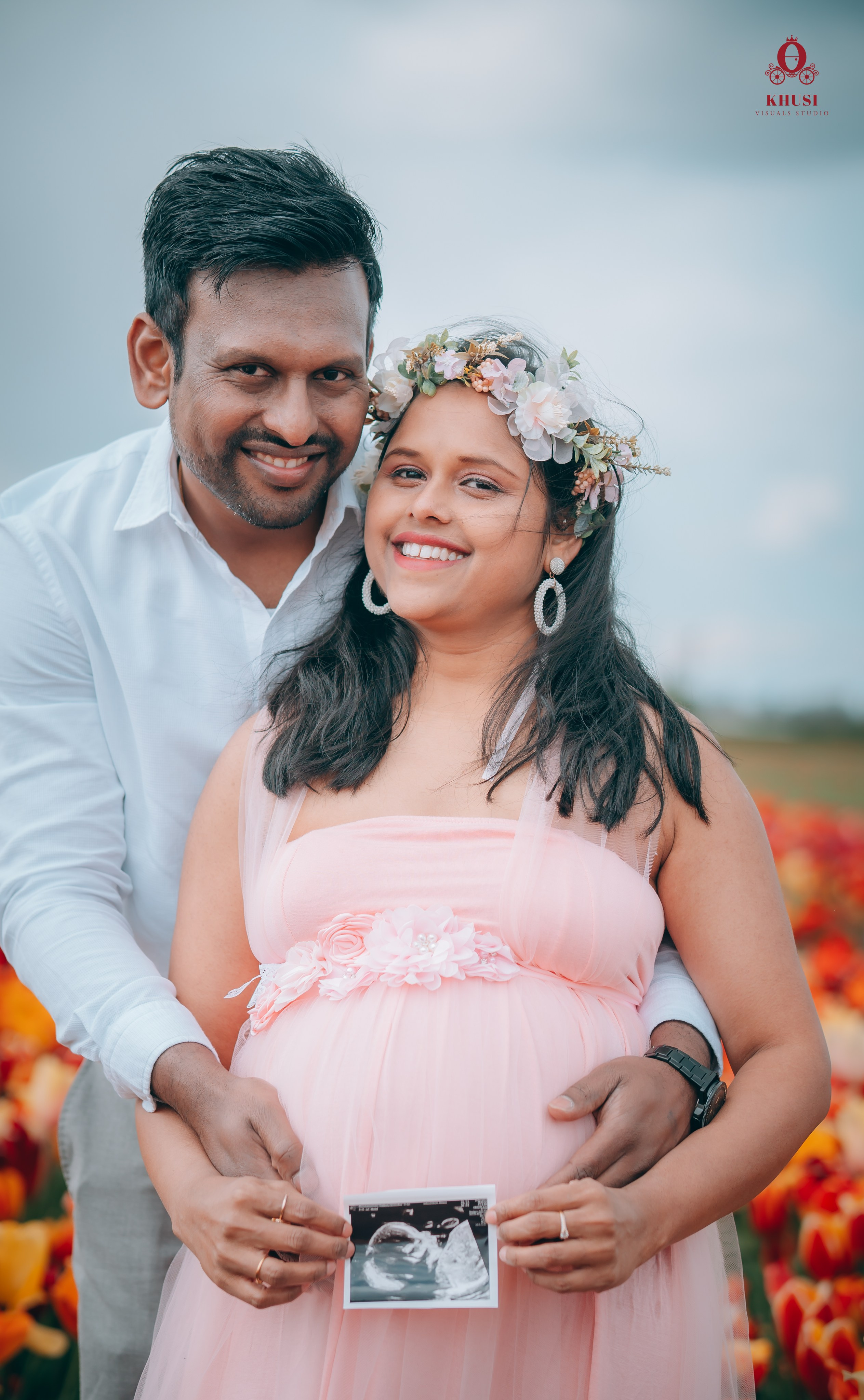 A pregnant couple holding sonogram in a tulip flower field in netherlands