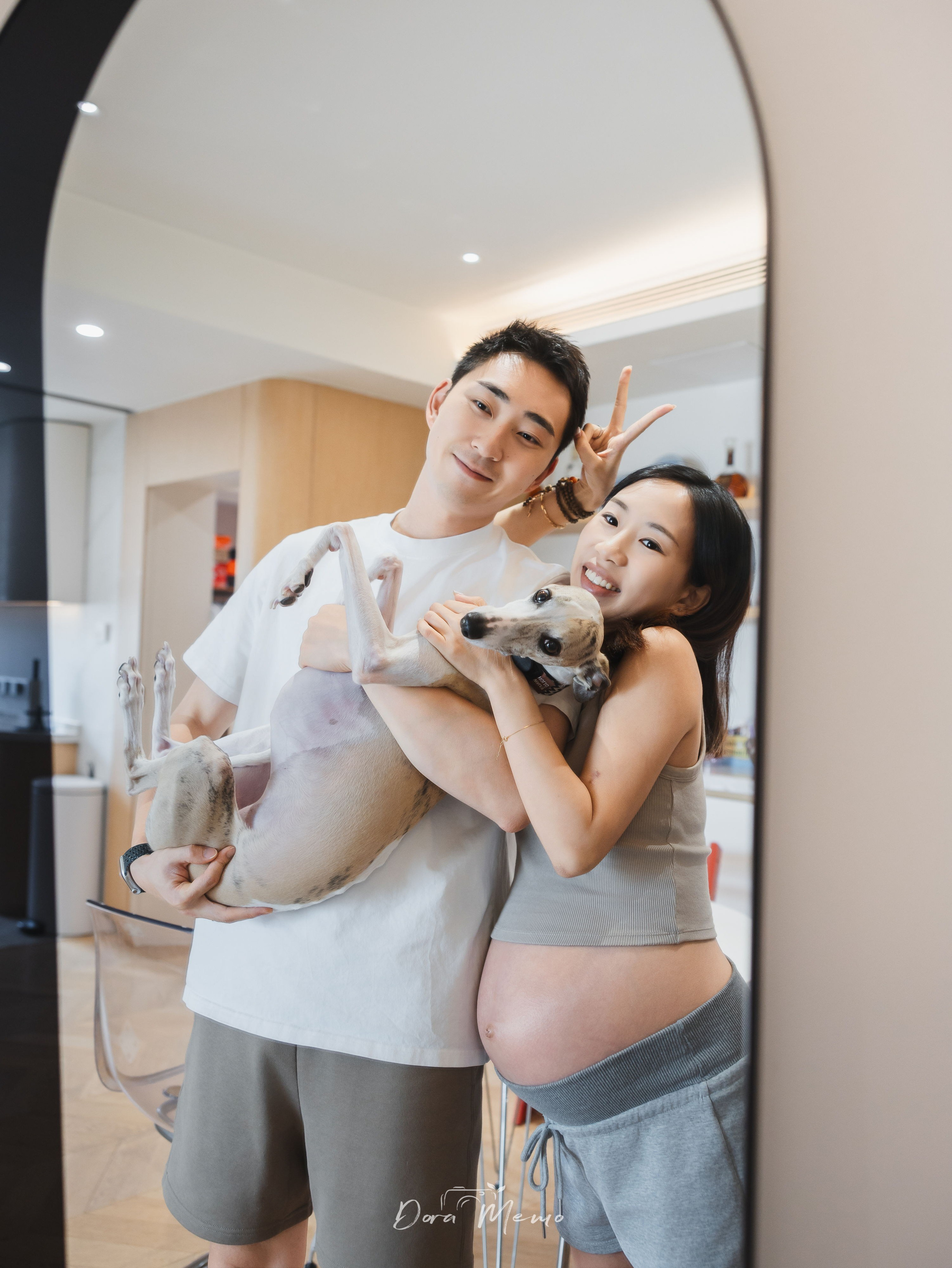Expecting parents holding their whippet at home, photographed by a Shanghai family photographer.