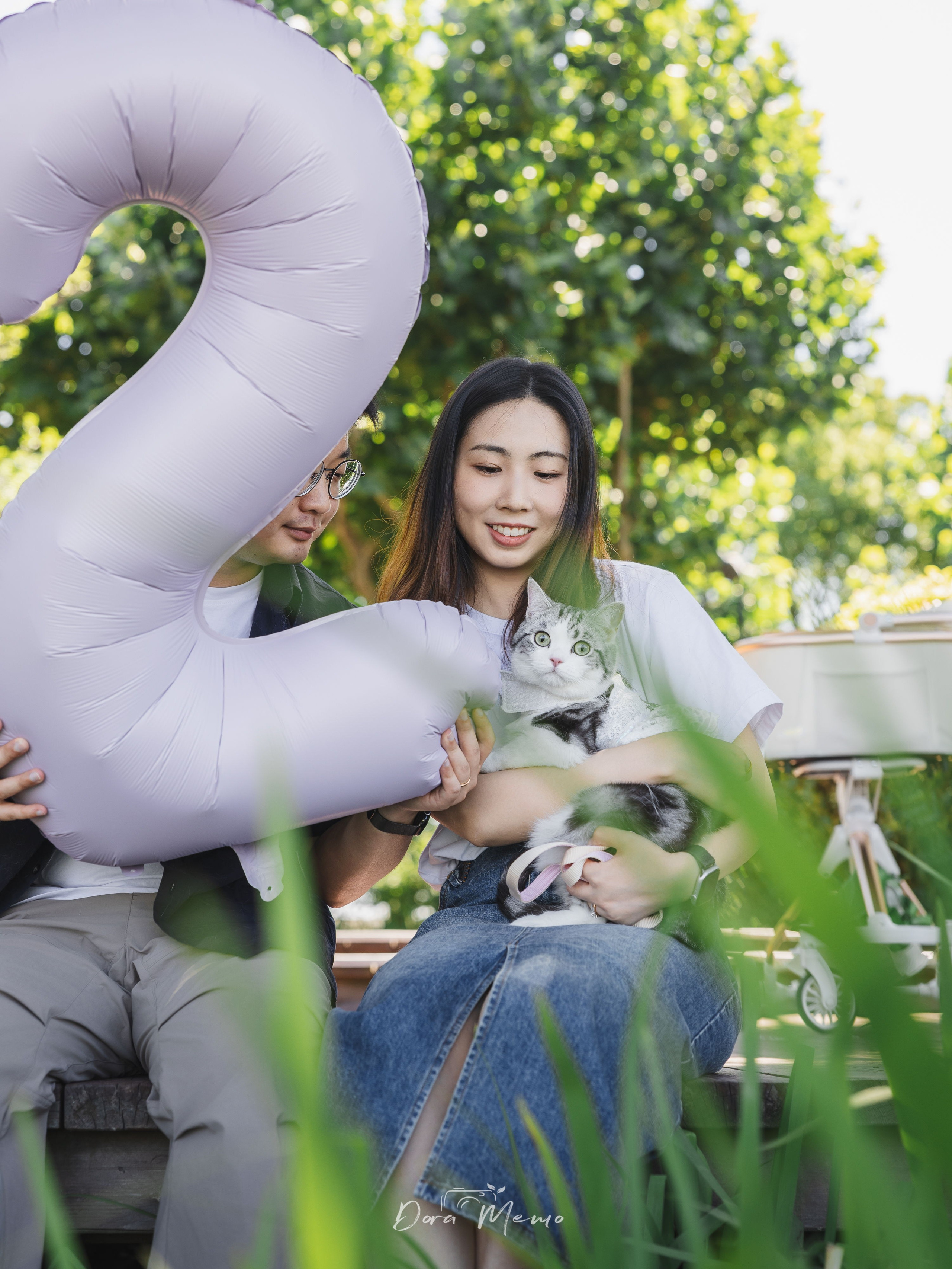 Family of three with a number "2" anniversary balloon, cat held in mom's lap