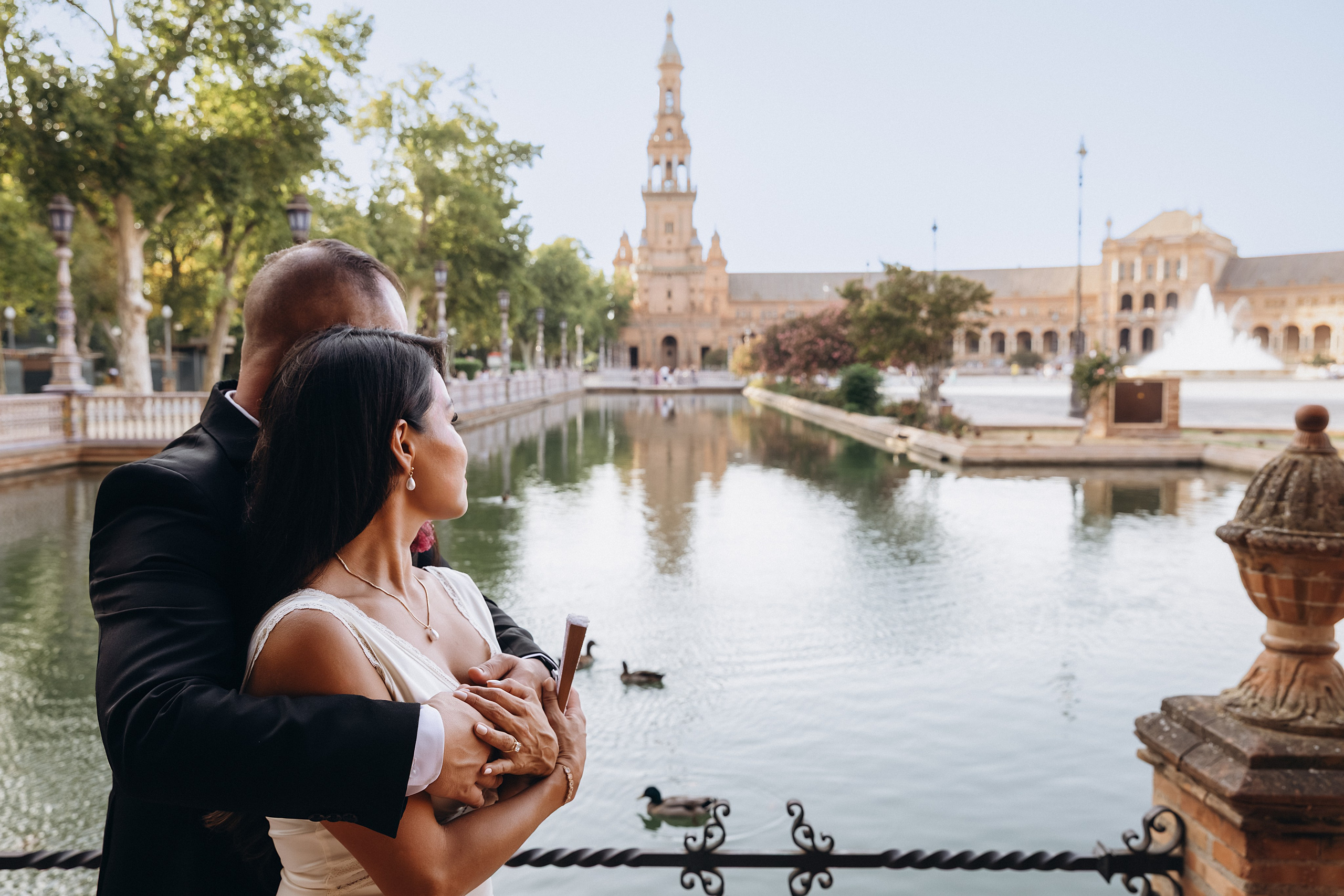 Romantic wedding photo of a couple embracing by the water at Plaza de España in Sevilla, Spain — a dreamy location for elegant and timeless wedding photoshoots in Seville.