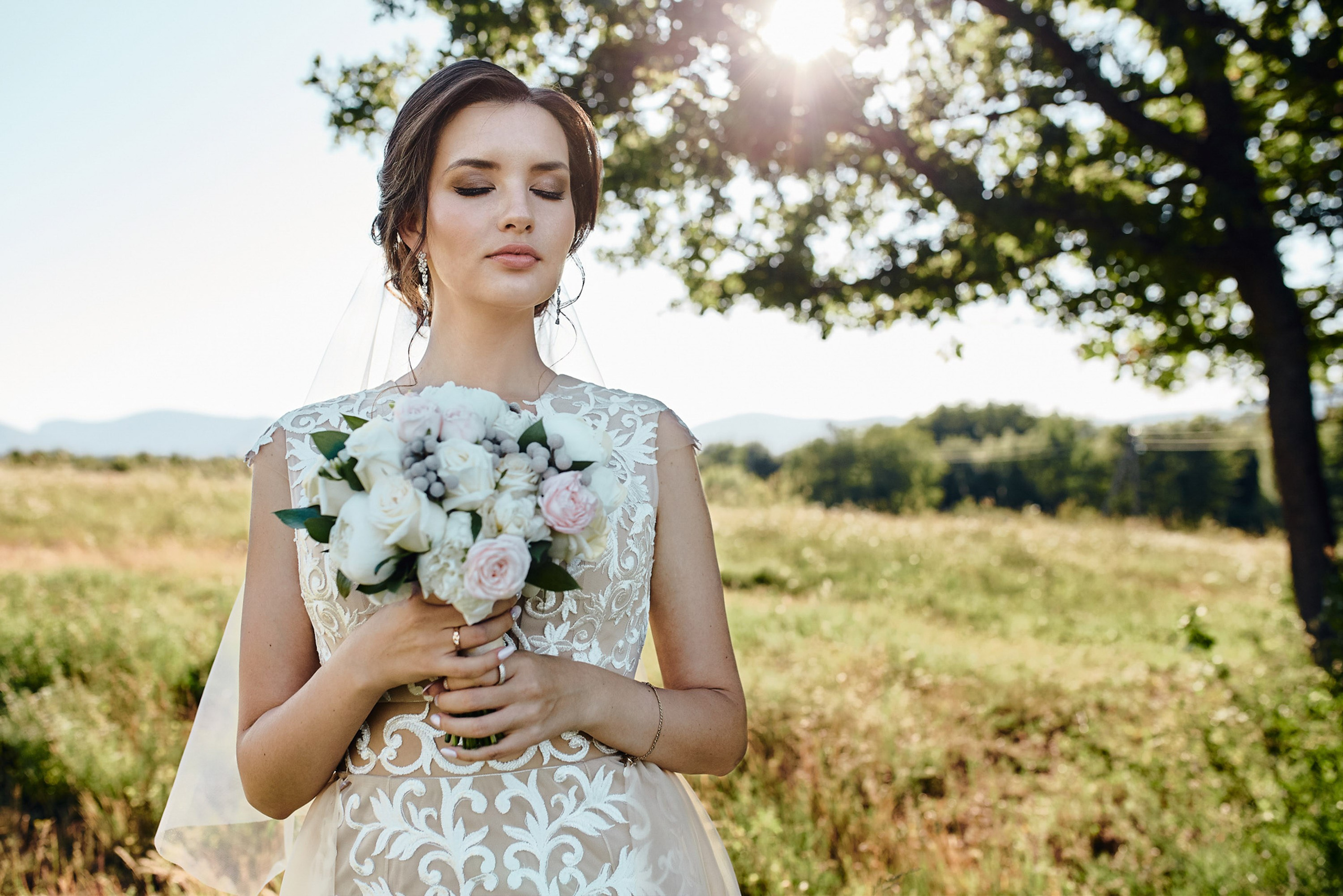 Bride holding bouquet in field, outdoor portrait