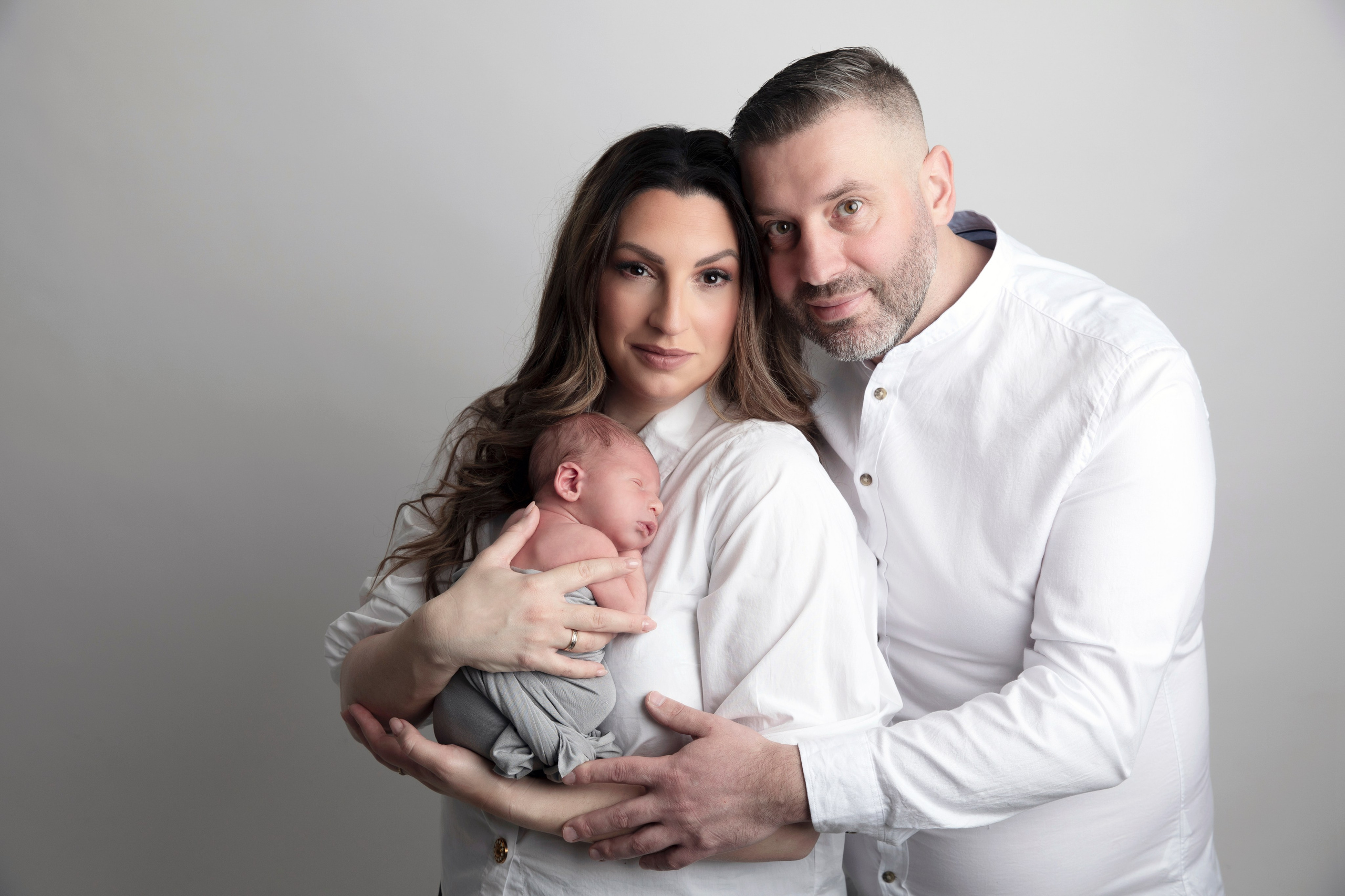 Syskonen håller sin nyfödda bror i famnen, ett fotografi från fototillfället av familjeband och glädje.