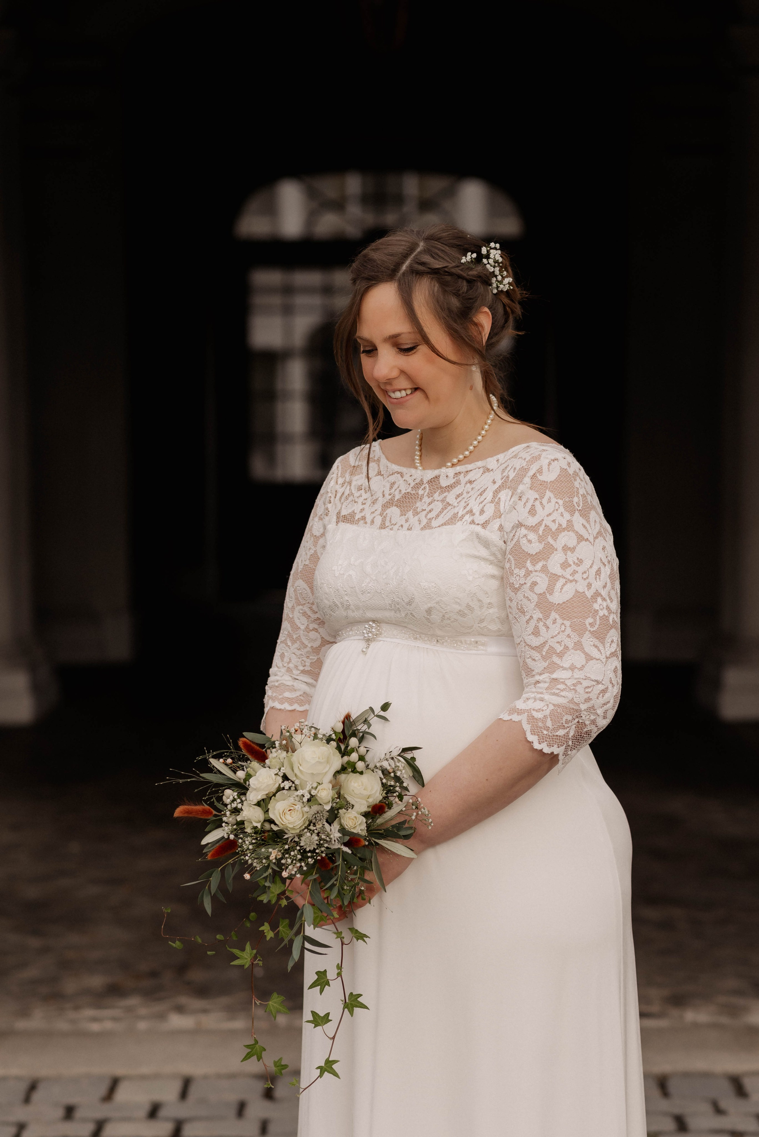 Eine schwangere Braut schaut auf ihr Bauch bei der Hochzeit in Ansbach