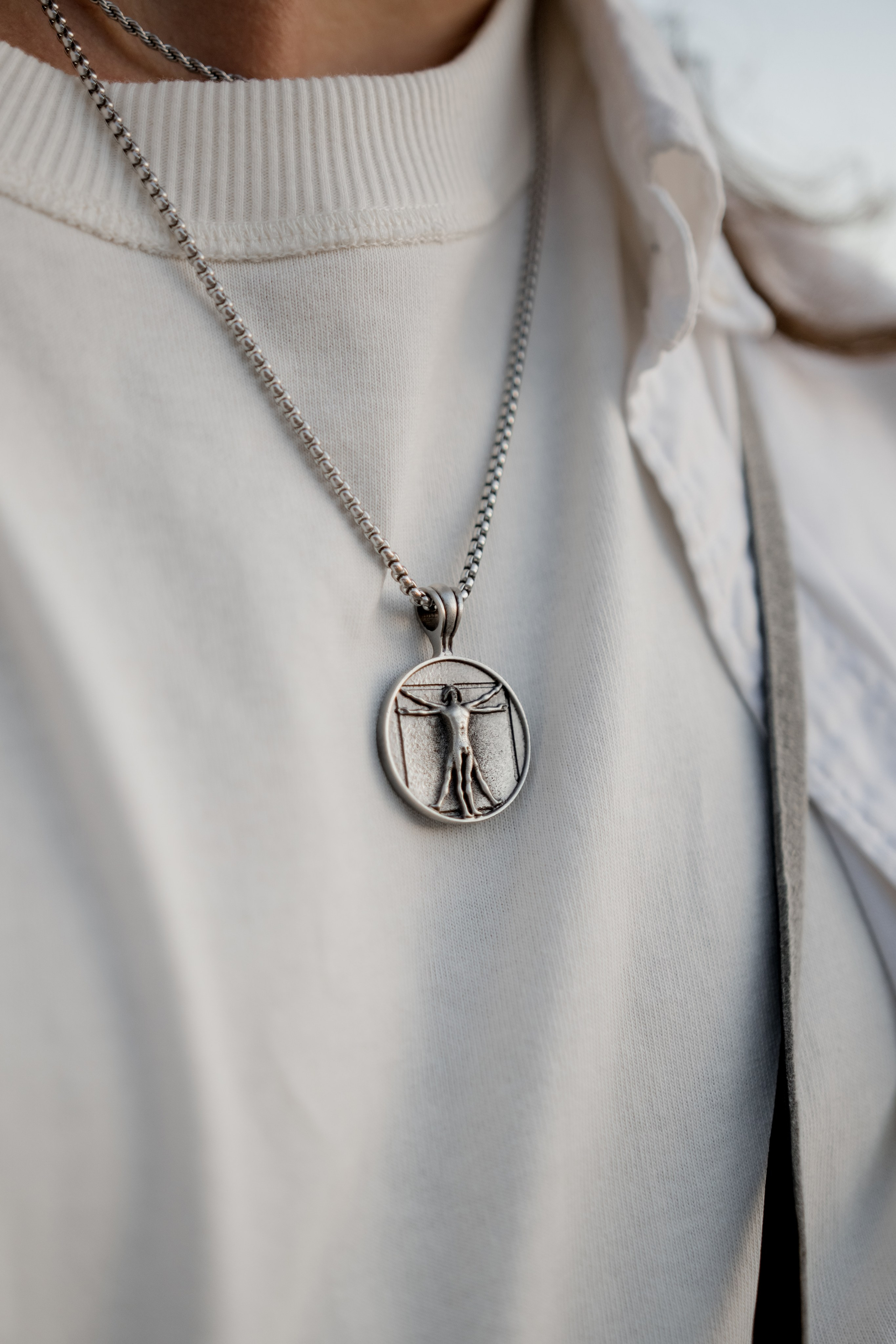 Layered silver necklaces styled over a white shirt, representing timeless and versatile jewelry fashion.