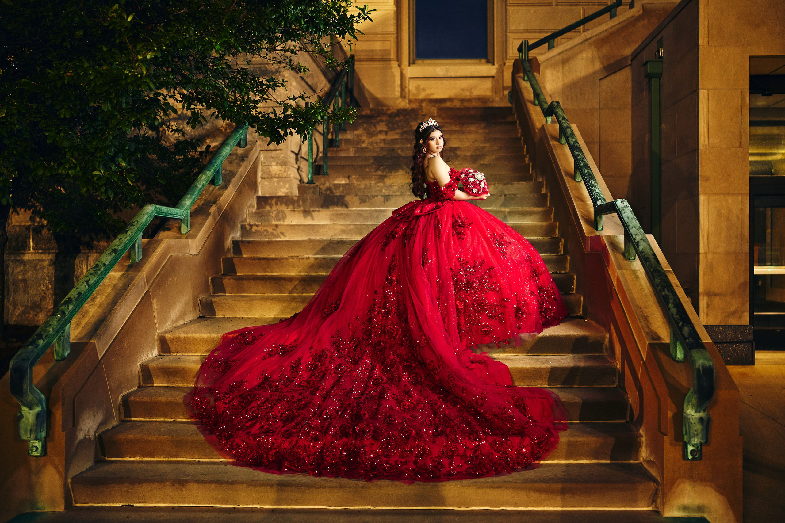 Editorial quinceañera session on outdoor stone stairs with voluminous red dress