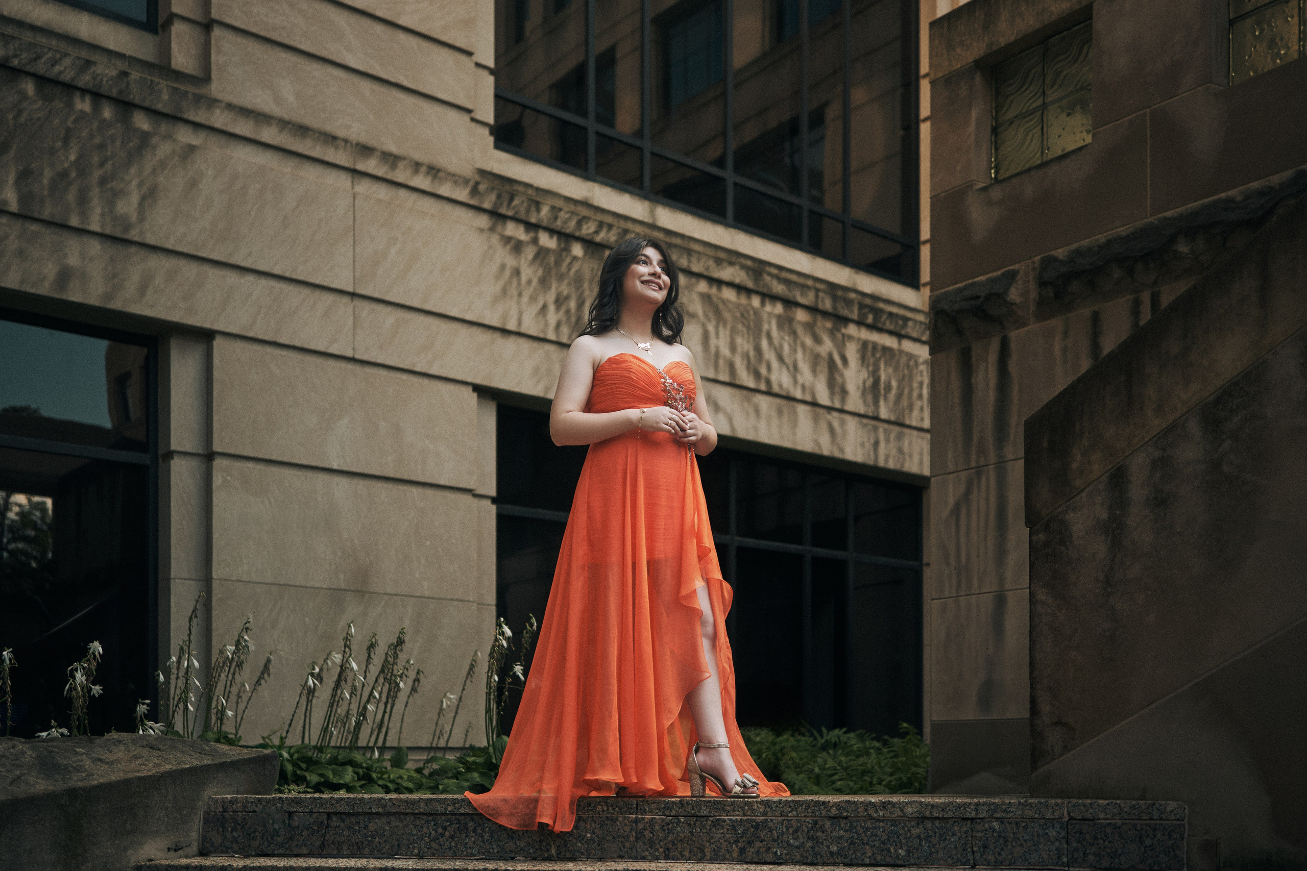 Editorial quinceañera fashion portrait in orange gown outdoors