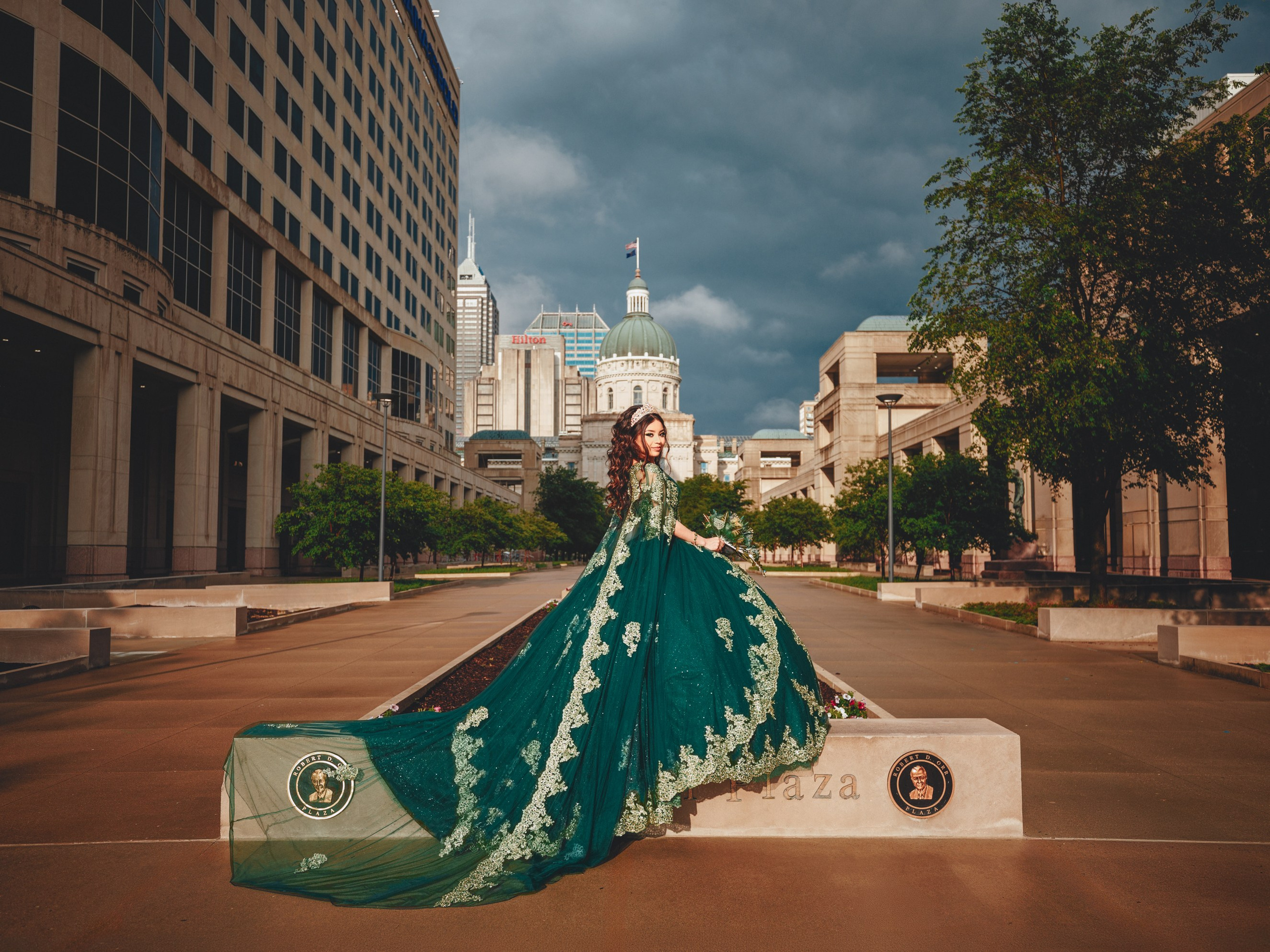 Dramatic quinceañera photoshoot at Indiana Statehouse Robert D. Orr Plaza with emerald gown train