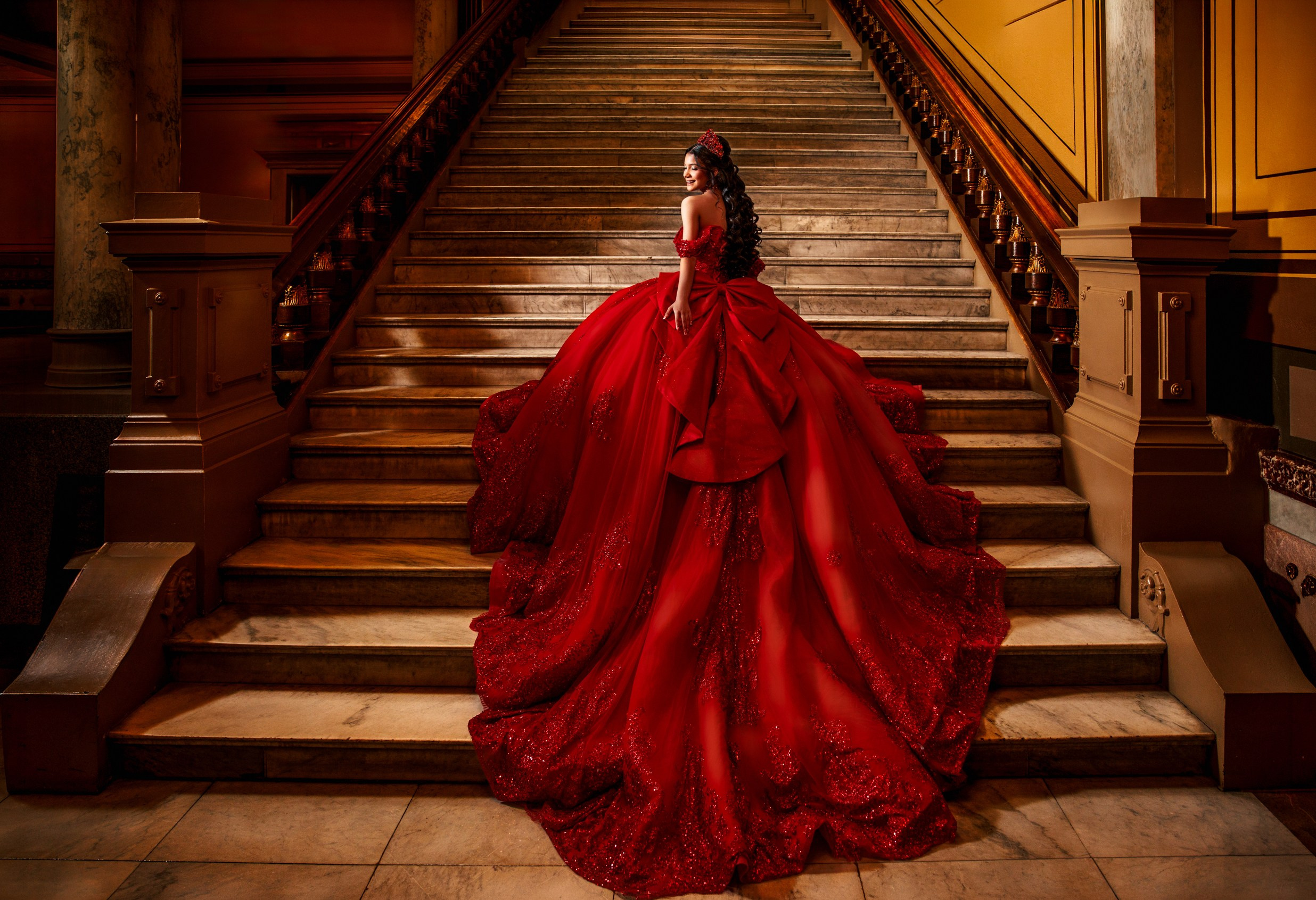 Dramatic fine art quinceañera portrait in sweeping red ballgown on historic grand staircase Indianapolis