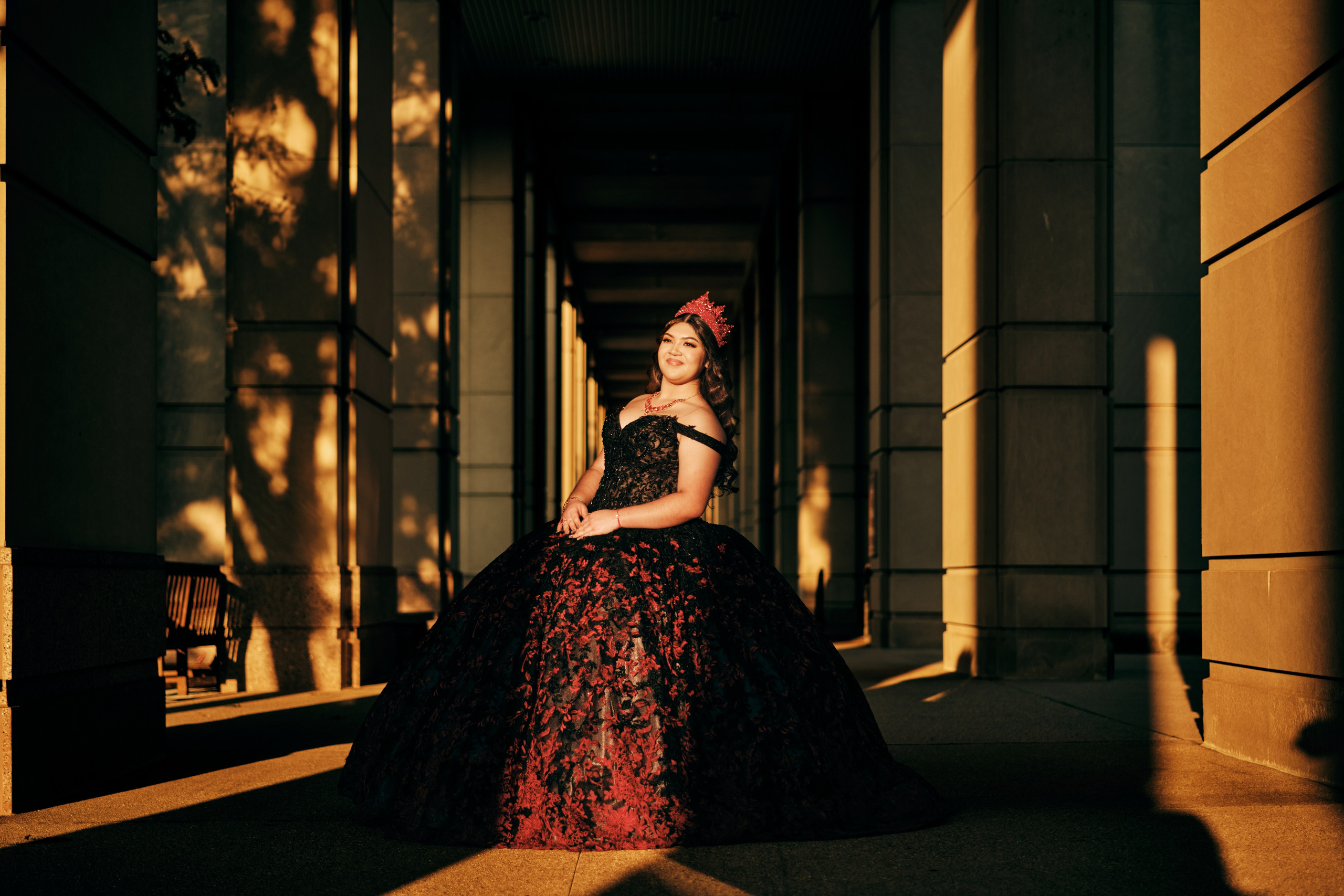 Cinematic quinceañera portrait with dramatic natural light between historic columns