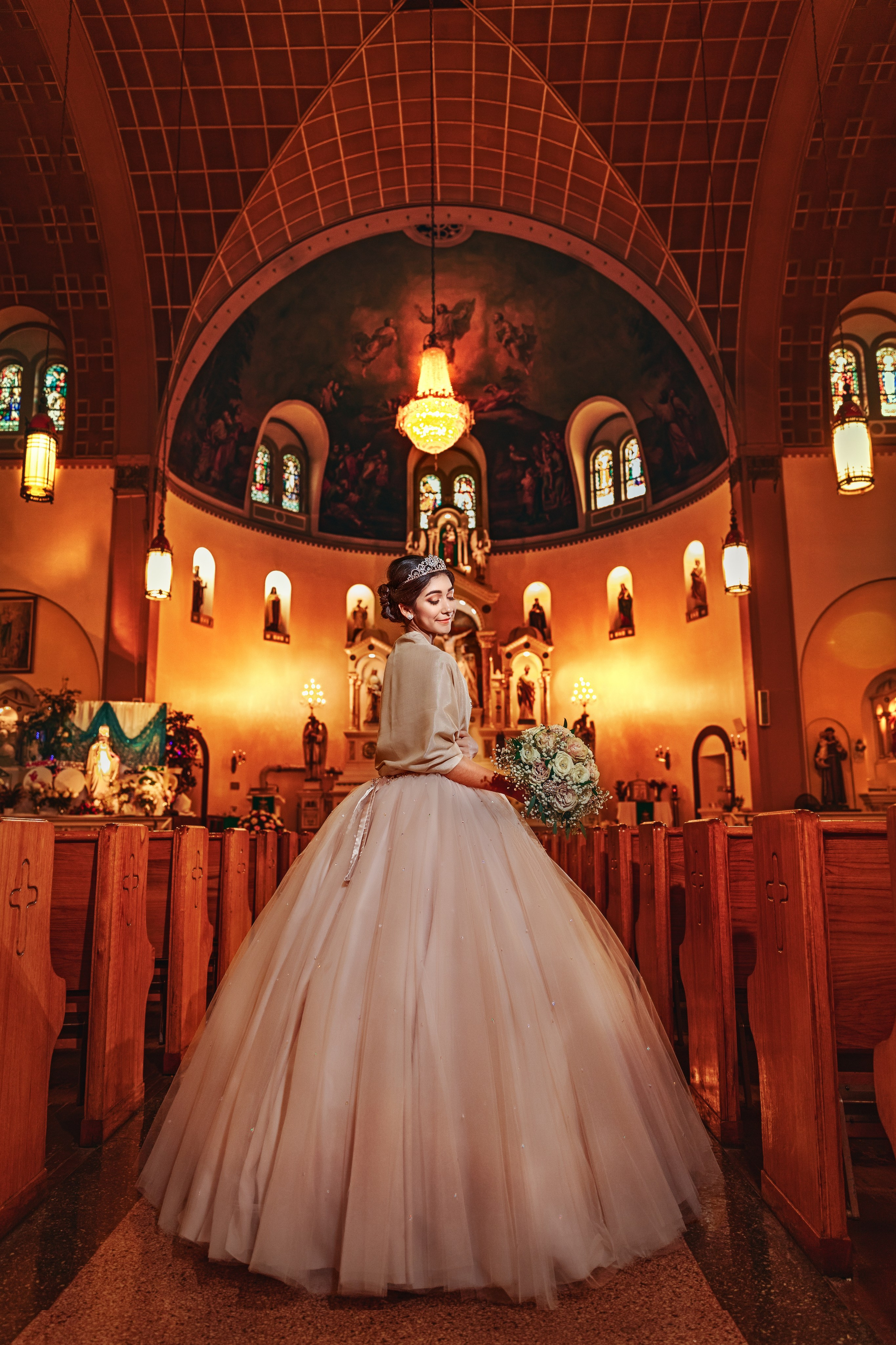 Fine art quinceañera in white gown inside illuminated architectural chapel