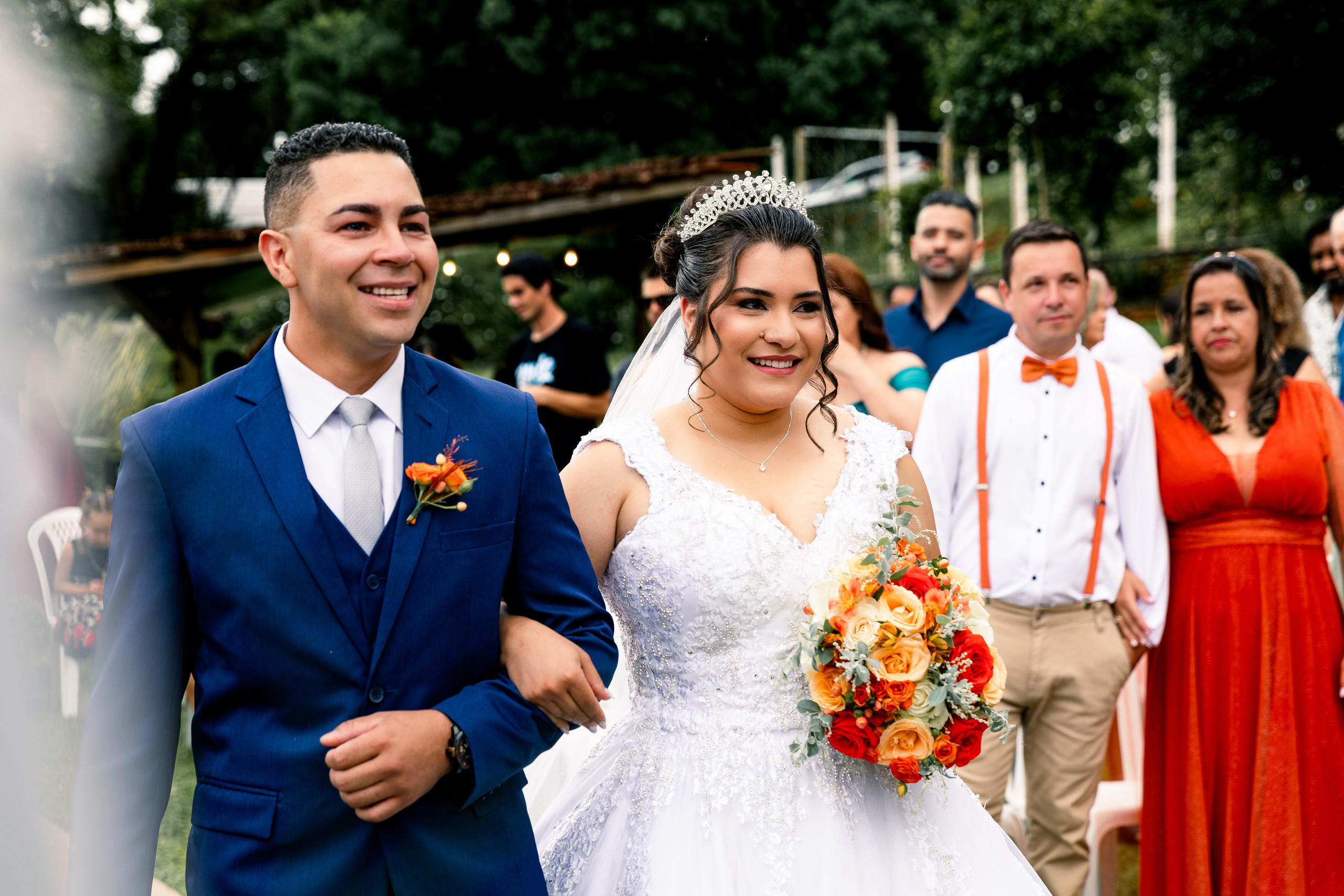 Noiva e noivo chegando ao altar, caminhando de mãos dadas em direção ao celebrante.