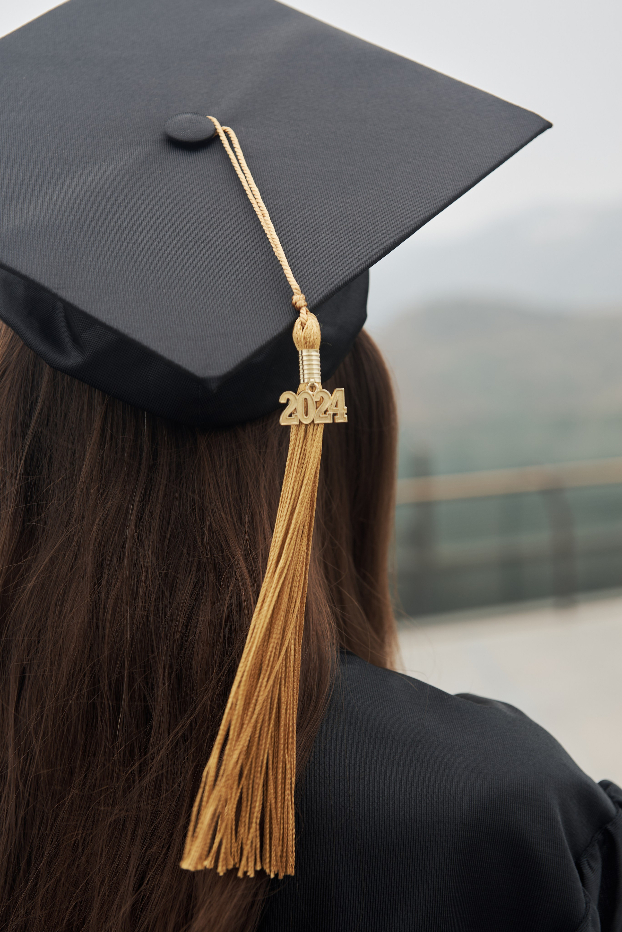 Dynamic graduation photo of a student tossing their cap in the air with downtown LA in view