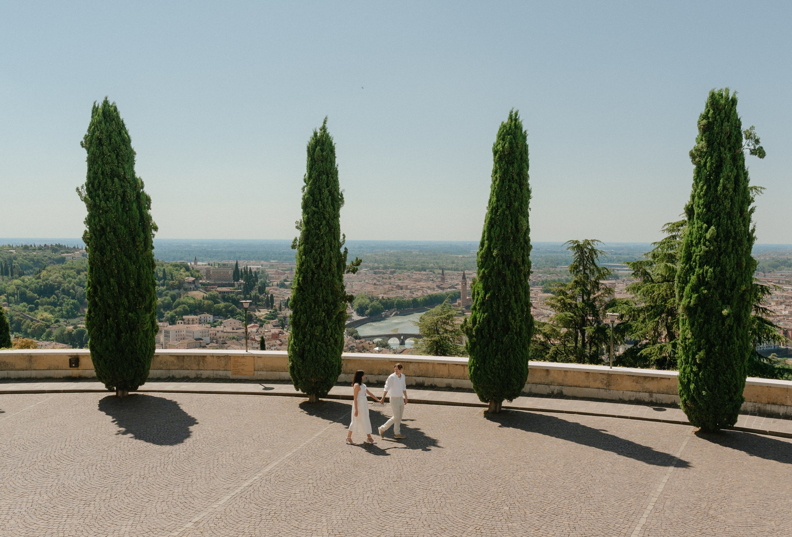 Joyful engagement photos captured from a panoramic viewpoint overlooking Verona, Italy.