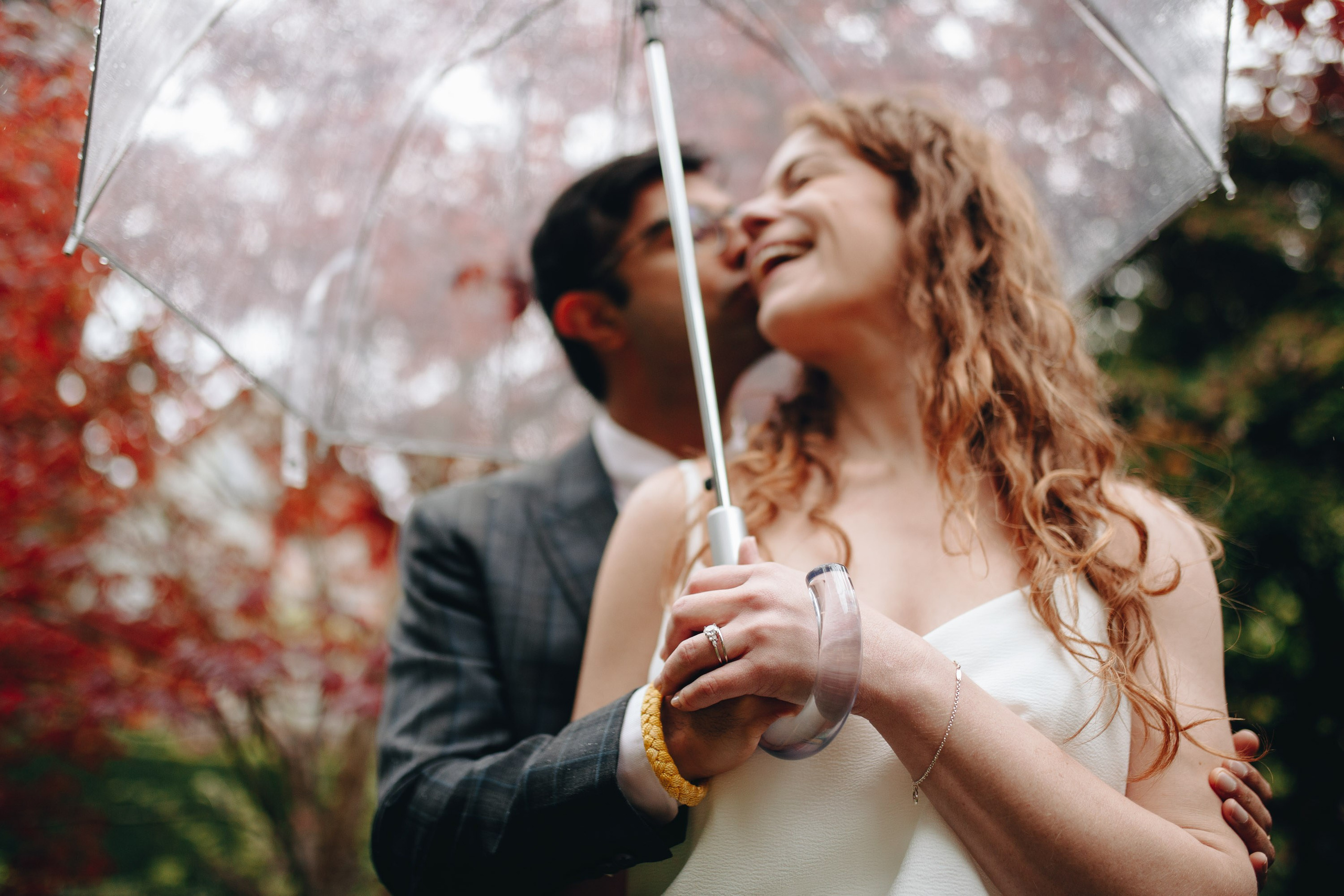 Bride under autumn leaves, playful wedding portrait