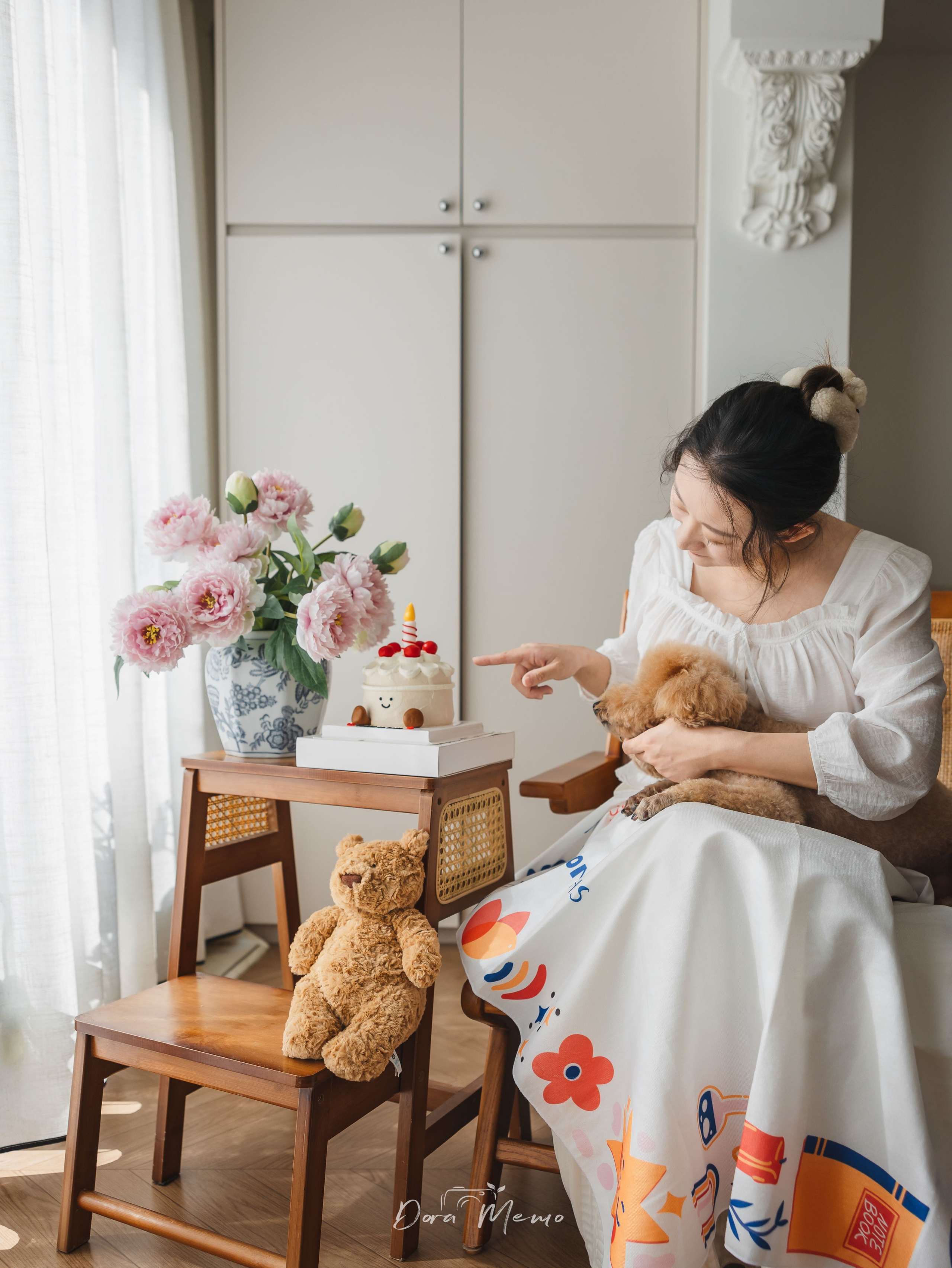Mother holding the family dog next to a small one-month milestone cake, celebrating a baby’s first month at home in Shanghai.