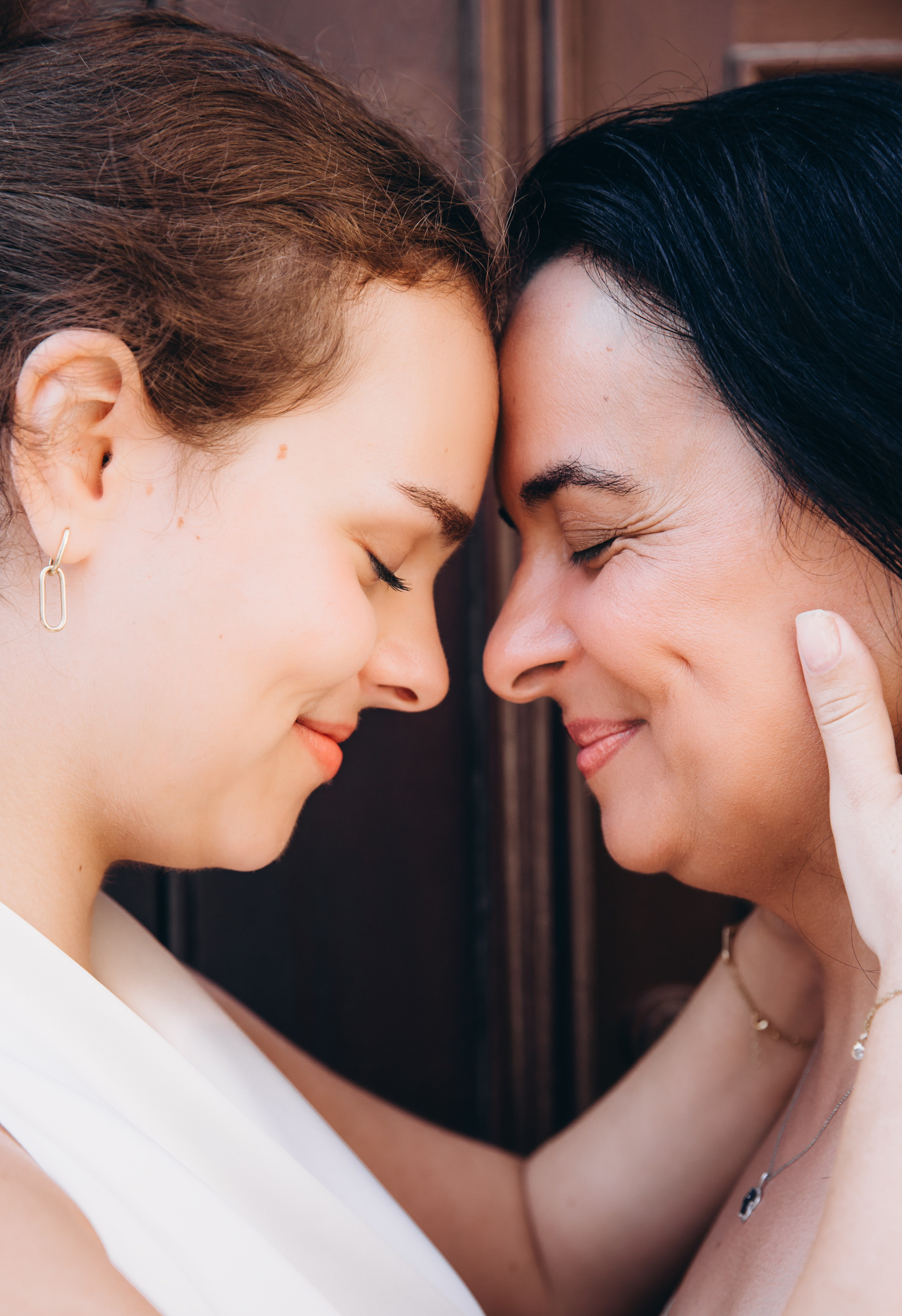 Retrato emocional de madre e hija en Alicante, España — primer plano de un momento tierno con las frentes juntas y ojos cerrados, simbolizando profundo amor familiar.