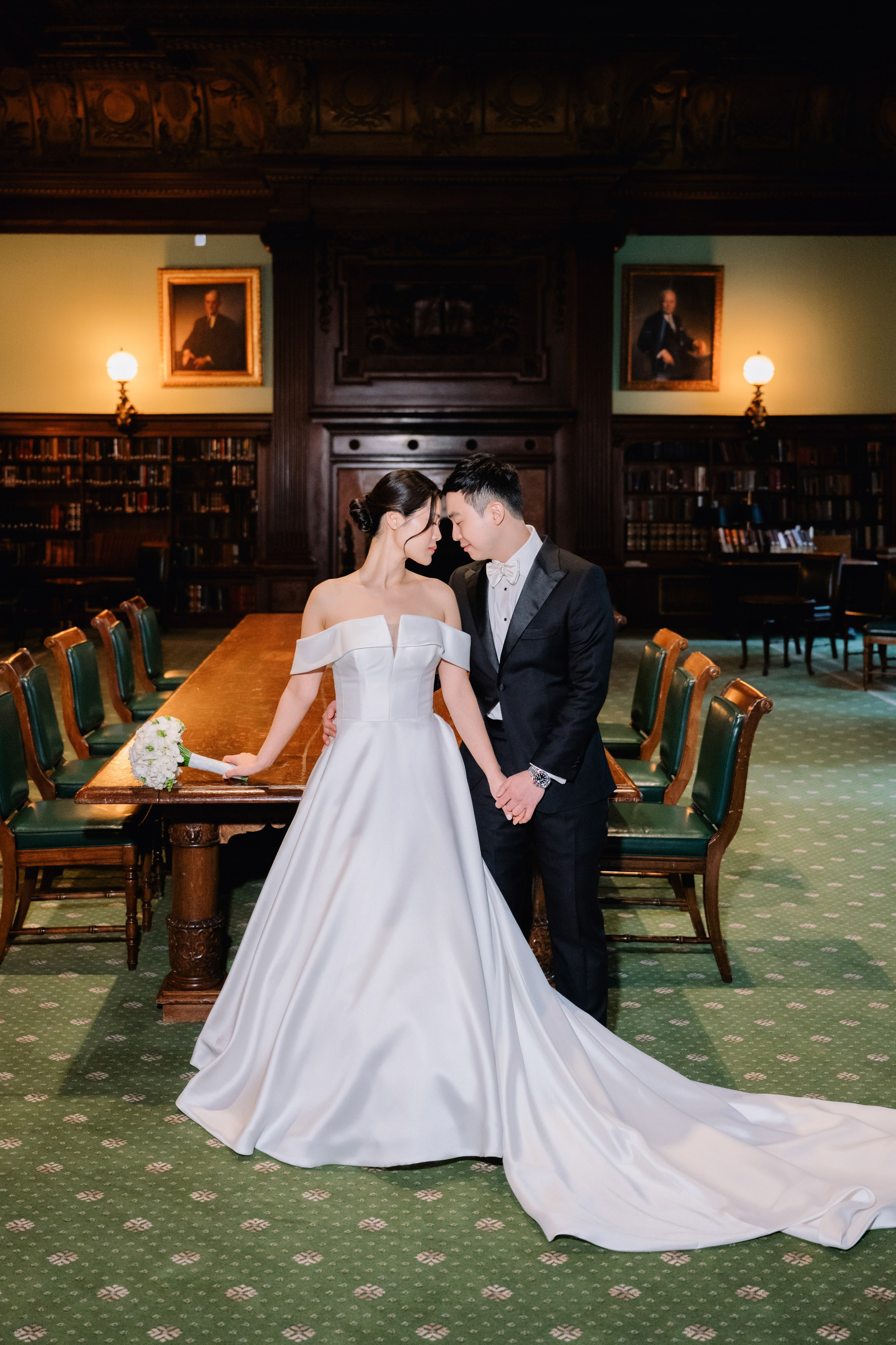 a bride and groom pose for a photo in the library