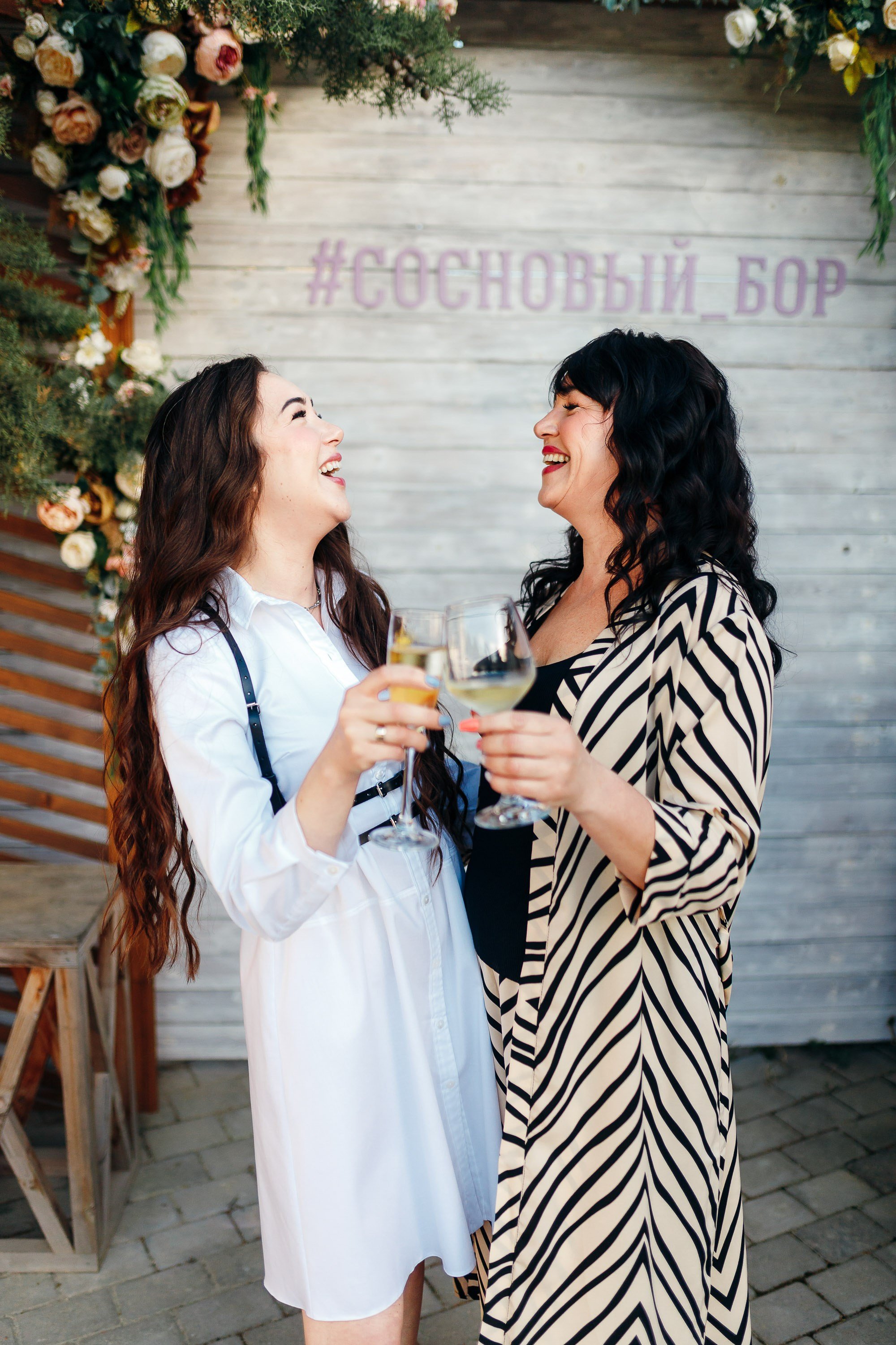 Two women toasting drinks, casual outdoor celebration