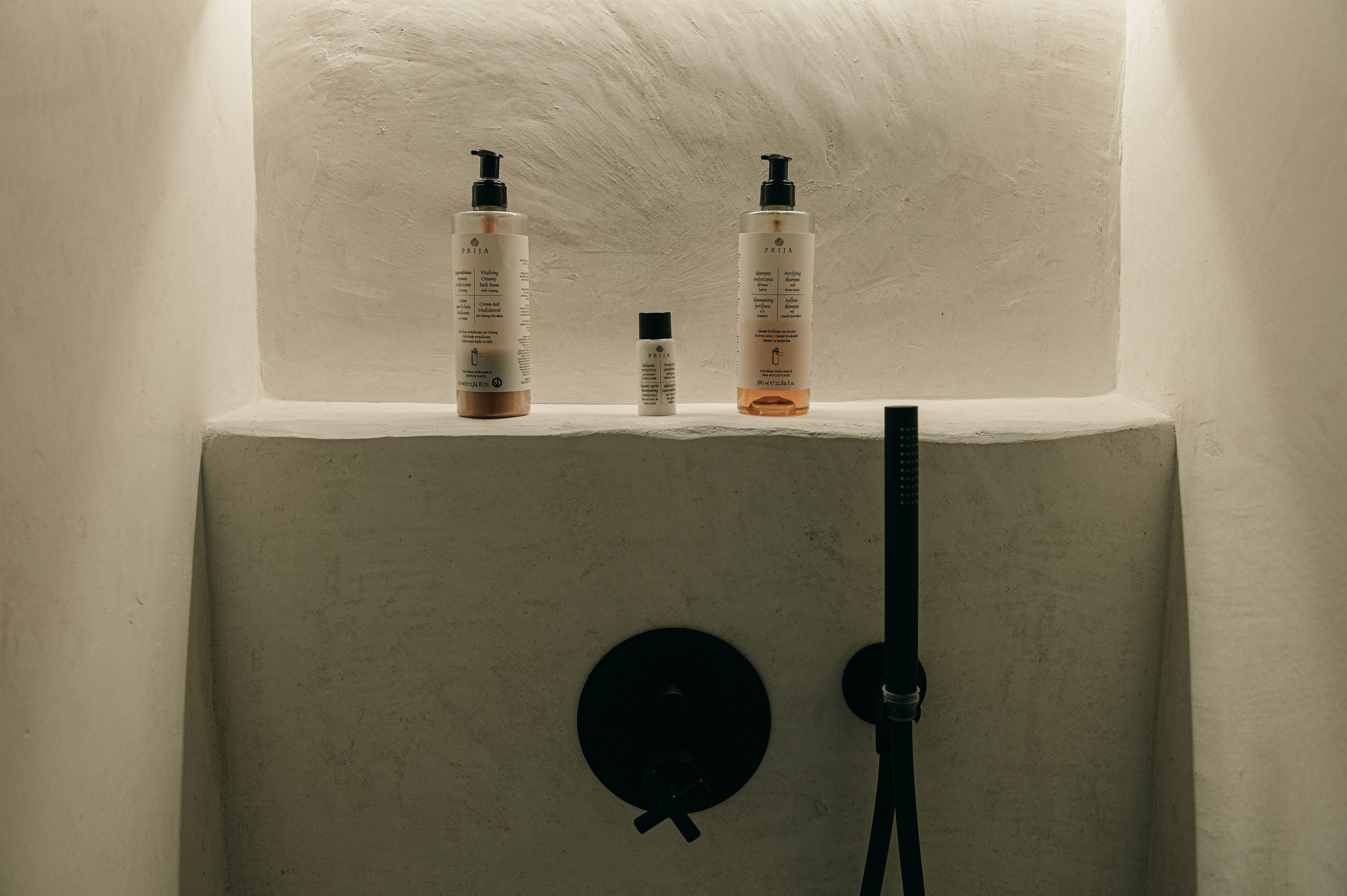 Minimalist walk-in shower with matte black fixtures and built-in niche, modern bathroom design in Puglia.