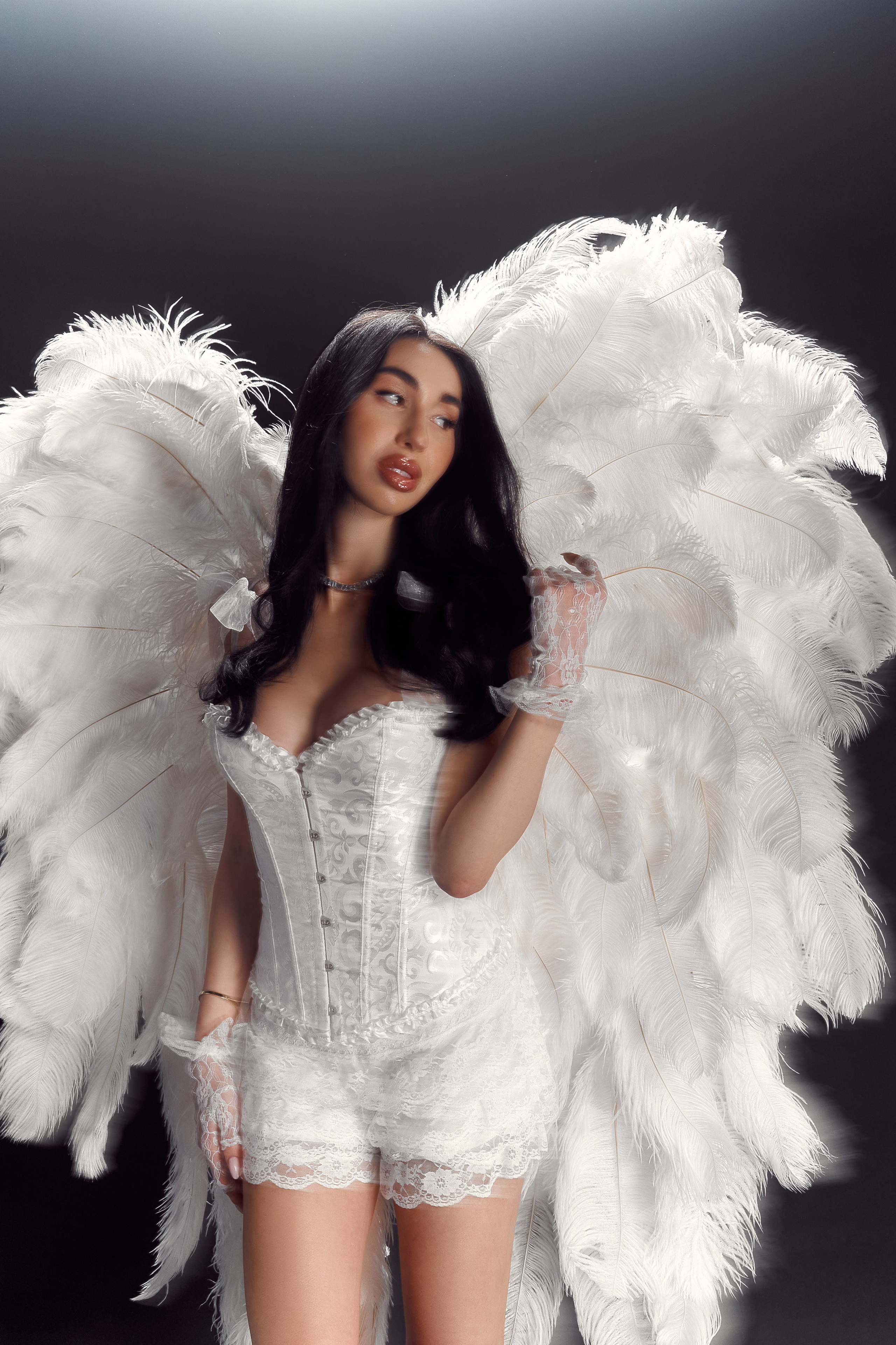 High-end editorial portrait of Ester Rogovaya with feather wings in a minimalist studio setting