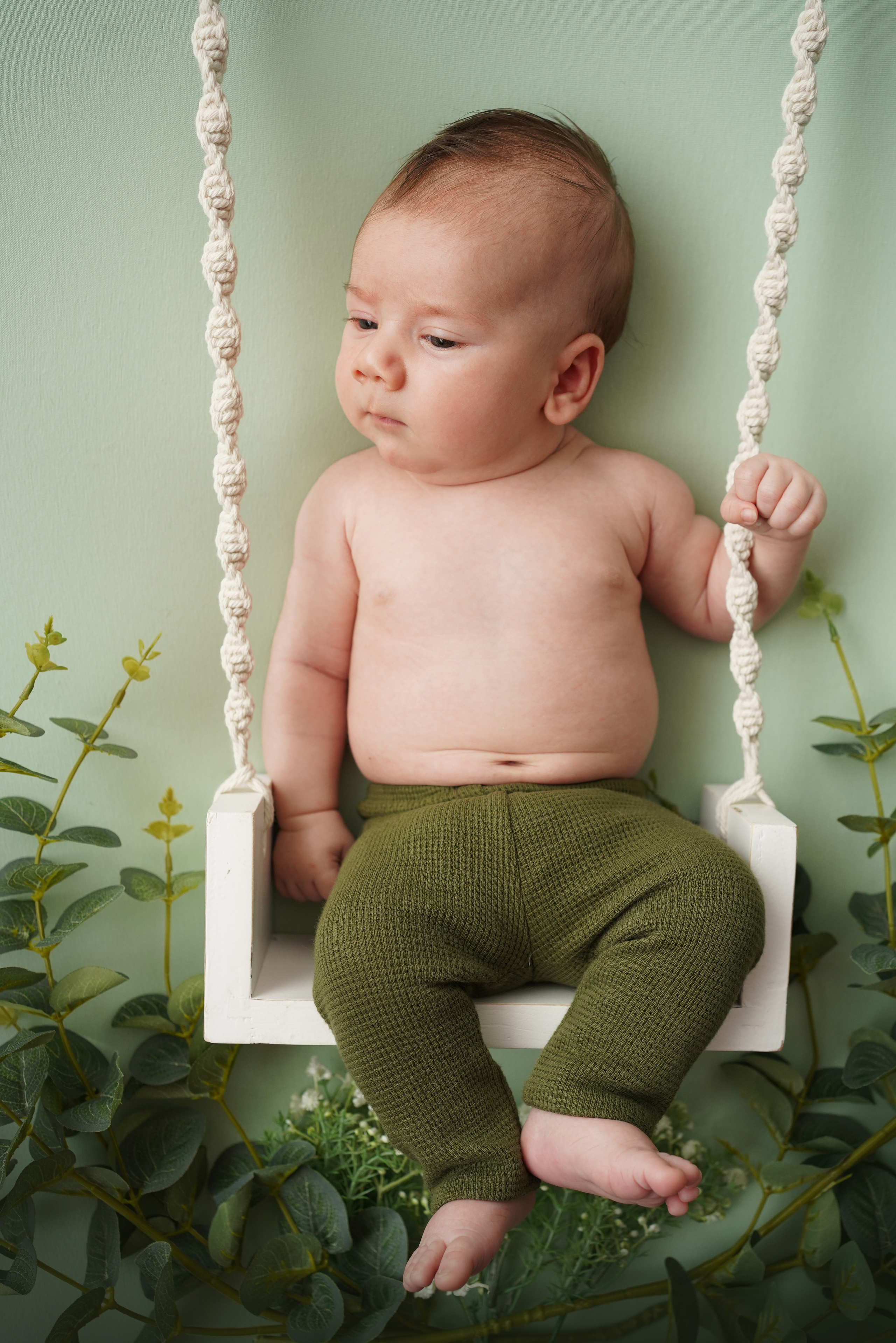 Spaß auf den Schaukeln: Ein glücklicher 2-Monate alter Junge