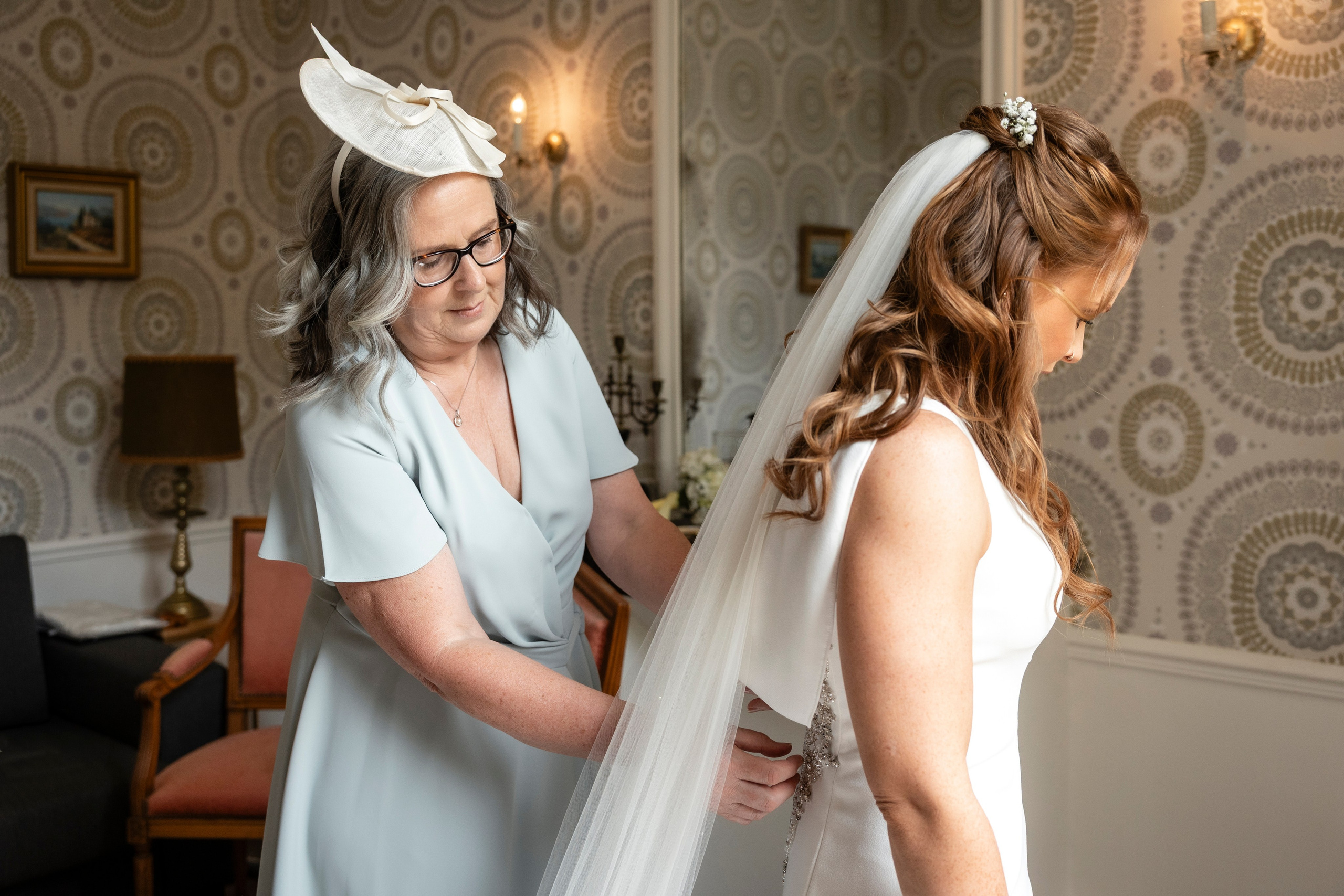 Mother of the bride in a hat beside her daughter before the ceremony