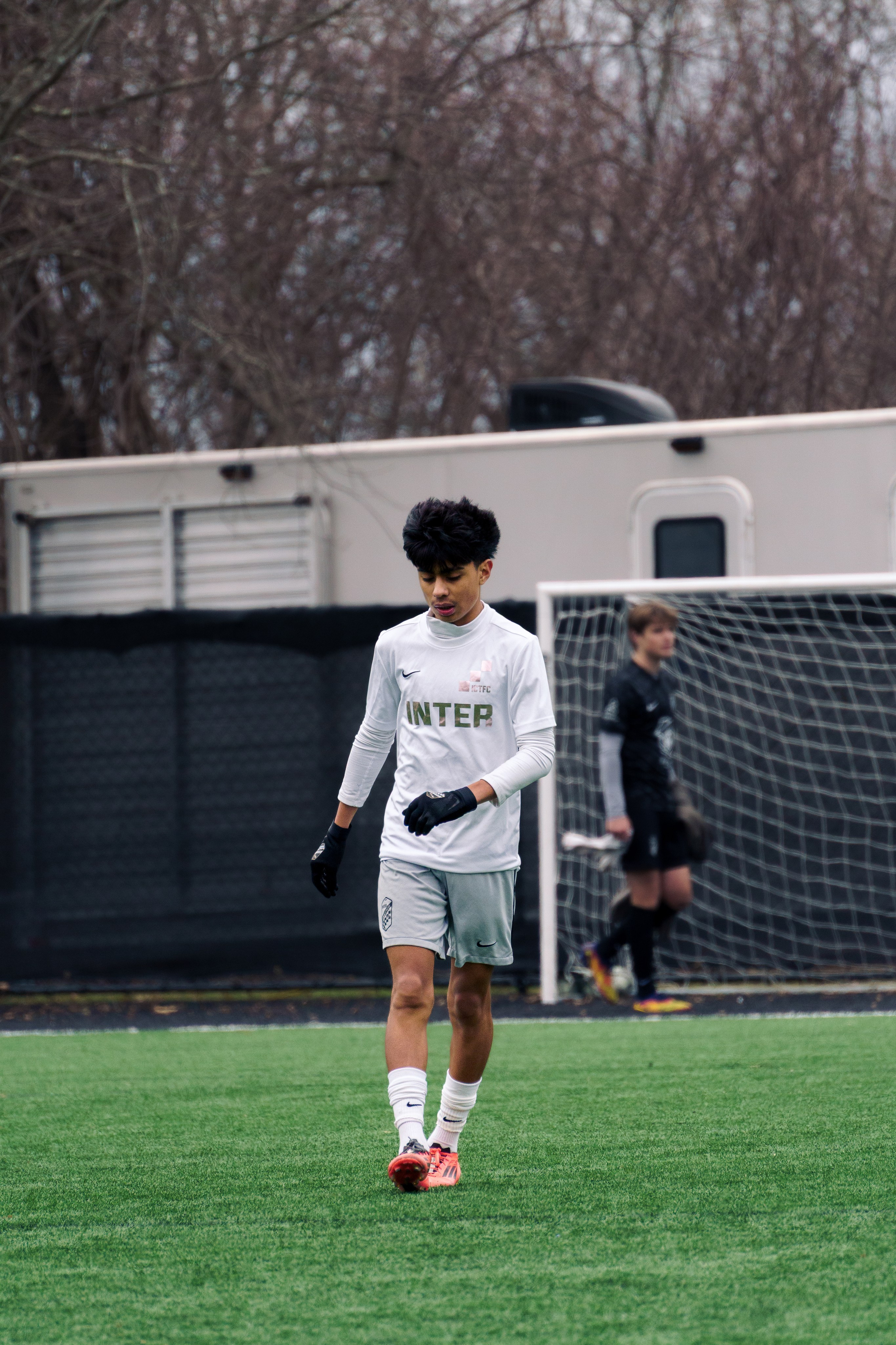Soccer player walking slowly with his head down and eyes closed, composing himself in a moment of focus during the match.