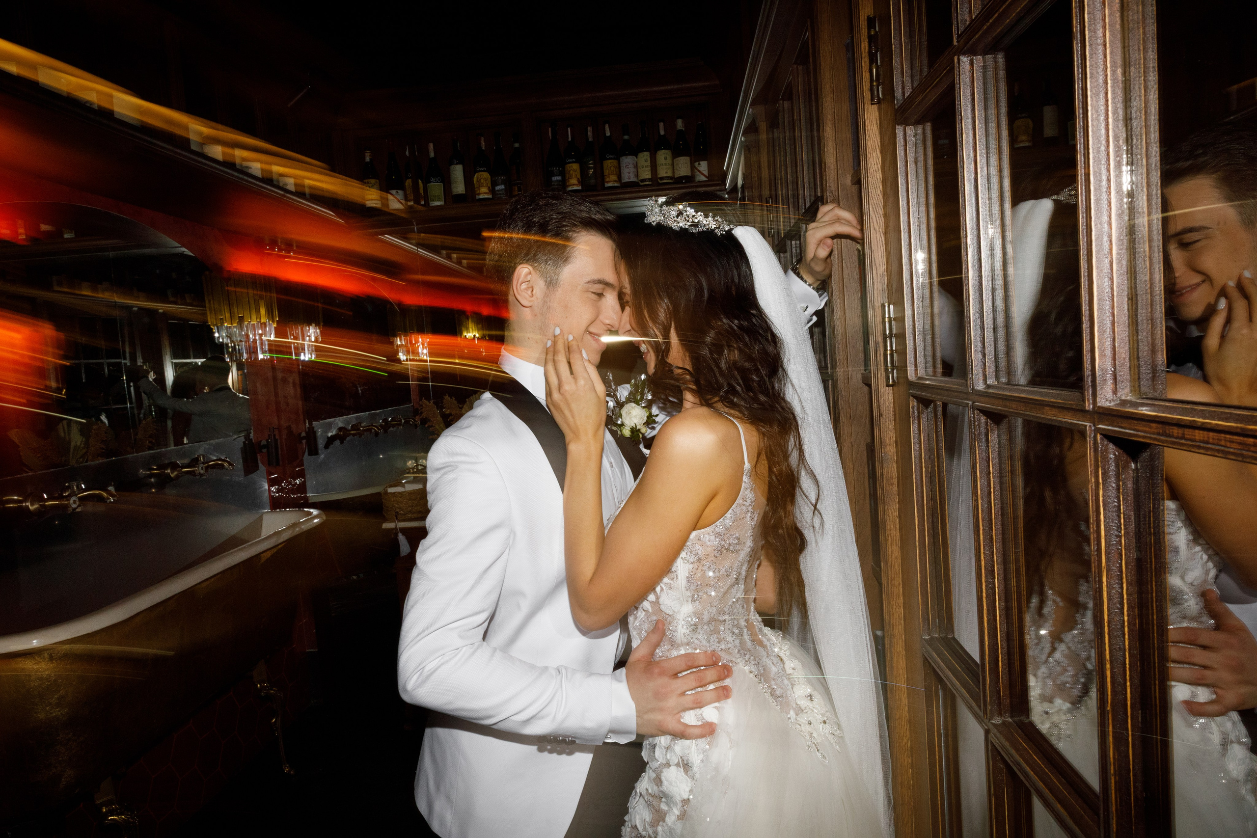 "Bride and groom embracing in a stylish venue with warm evening lighting."